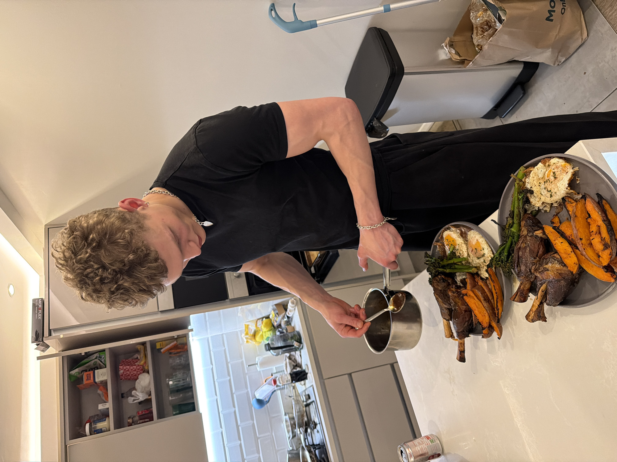 Young man plates lamb dinner in London kitchen