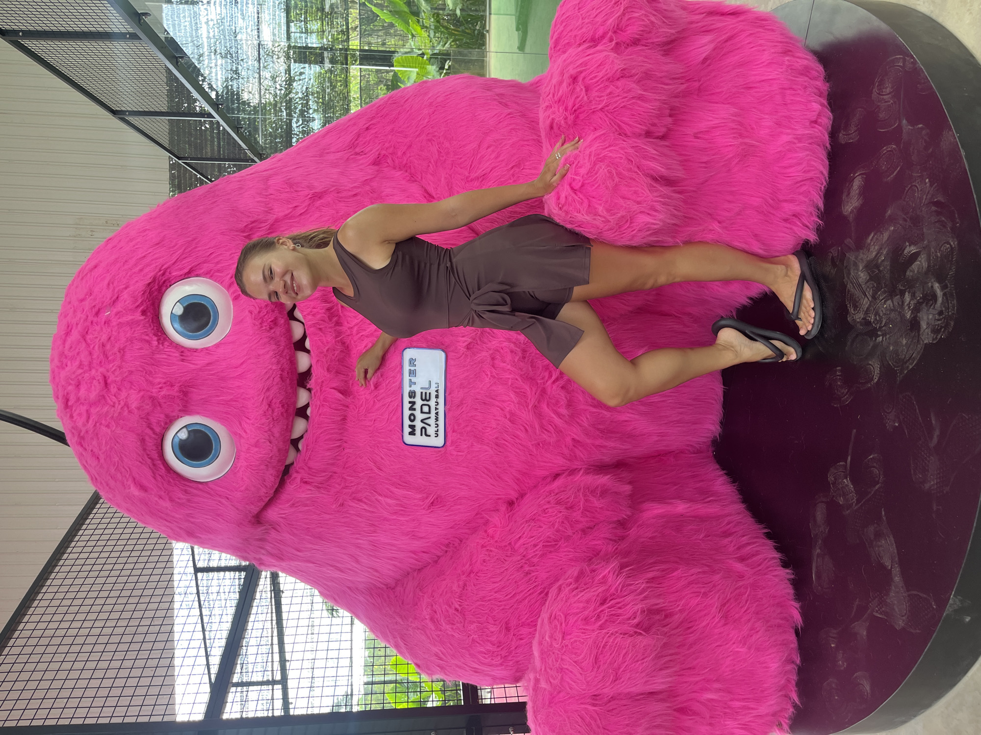 Woman poses with pink monster statue at Indonesian sports facility