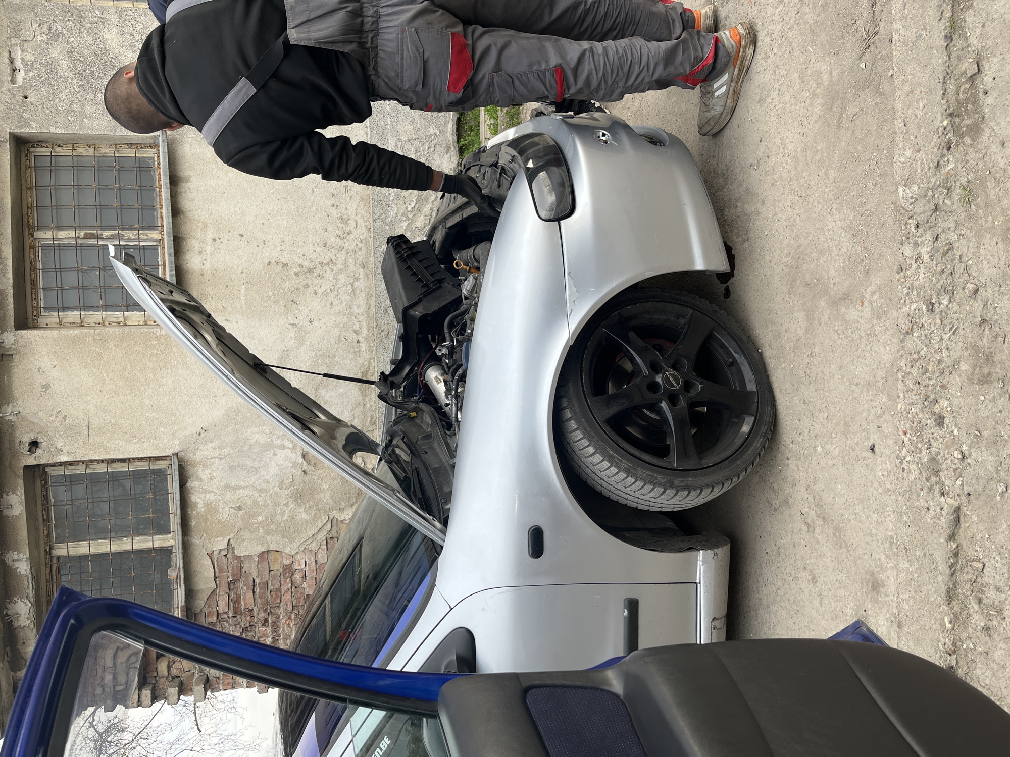 Man repairs damaged silver car in Pleven, Bulgaria