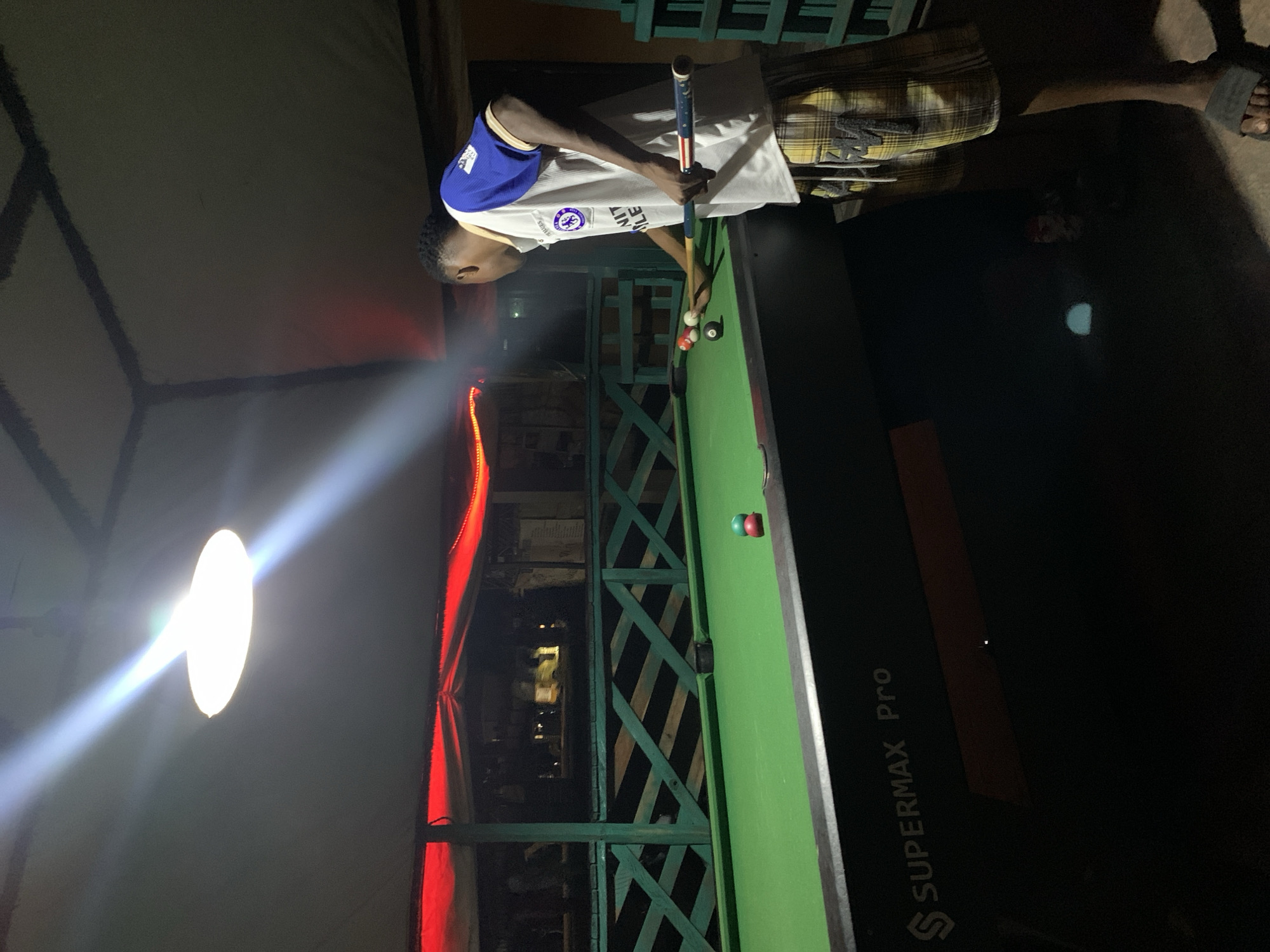 Nightlife along Lokoja's streets: pool, vendors, and passing traffic