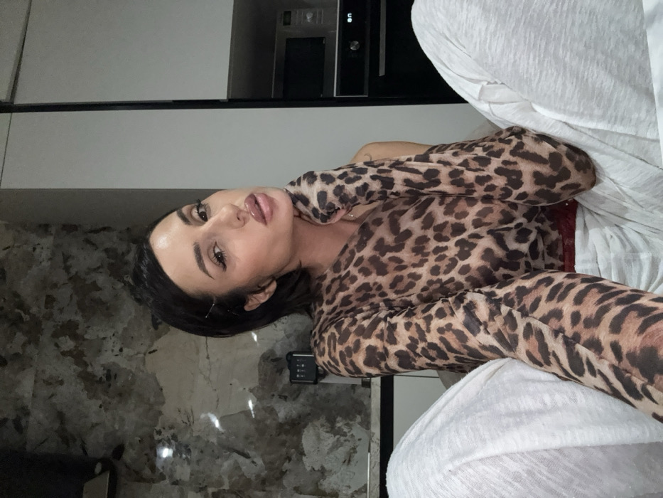 Woman poses in kitchen wearing leopard-print top