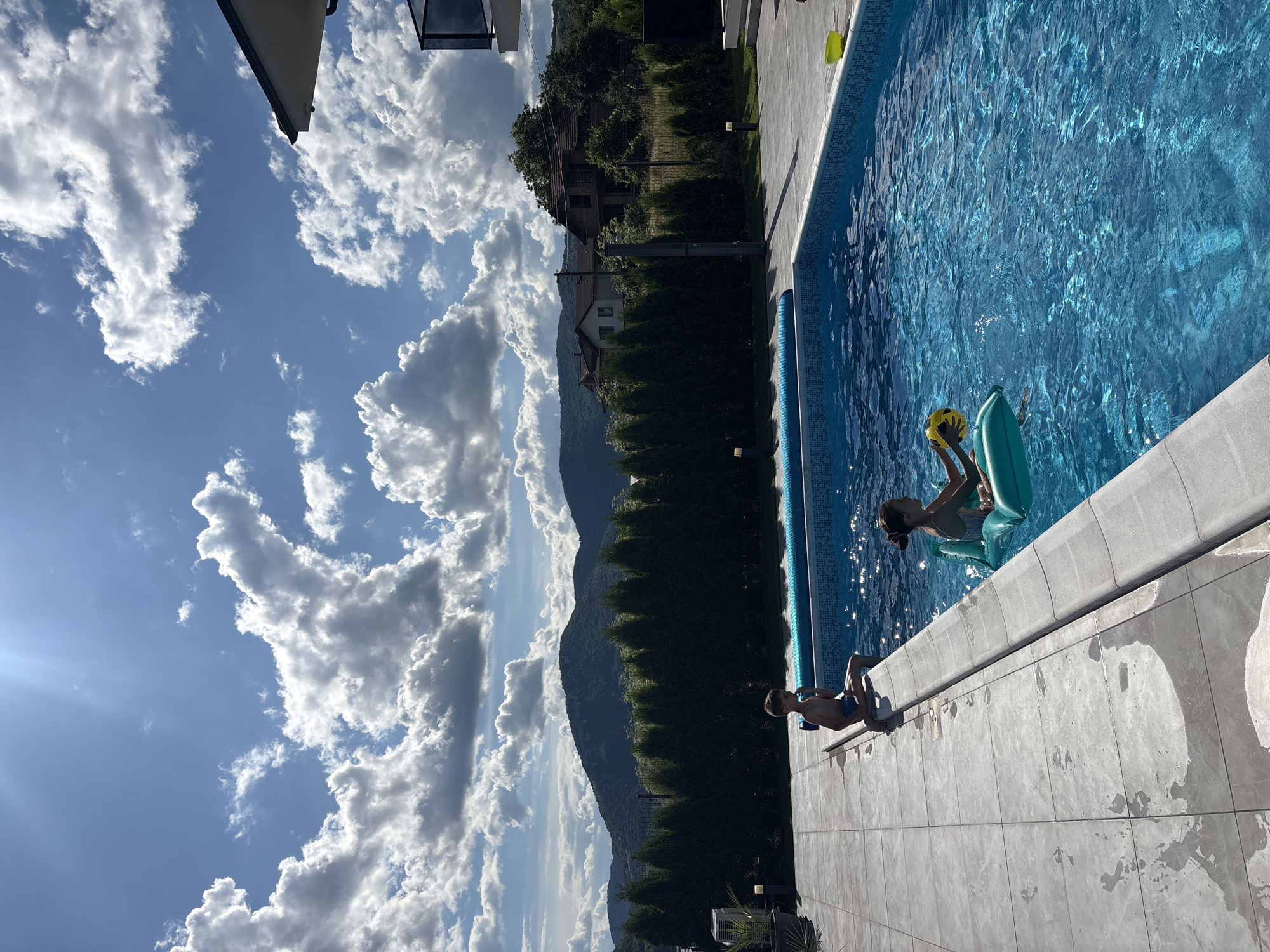 Children play at lakeside pool amid scenic mountain views