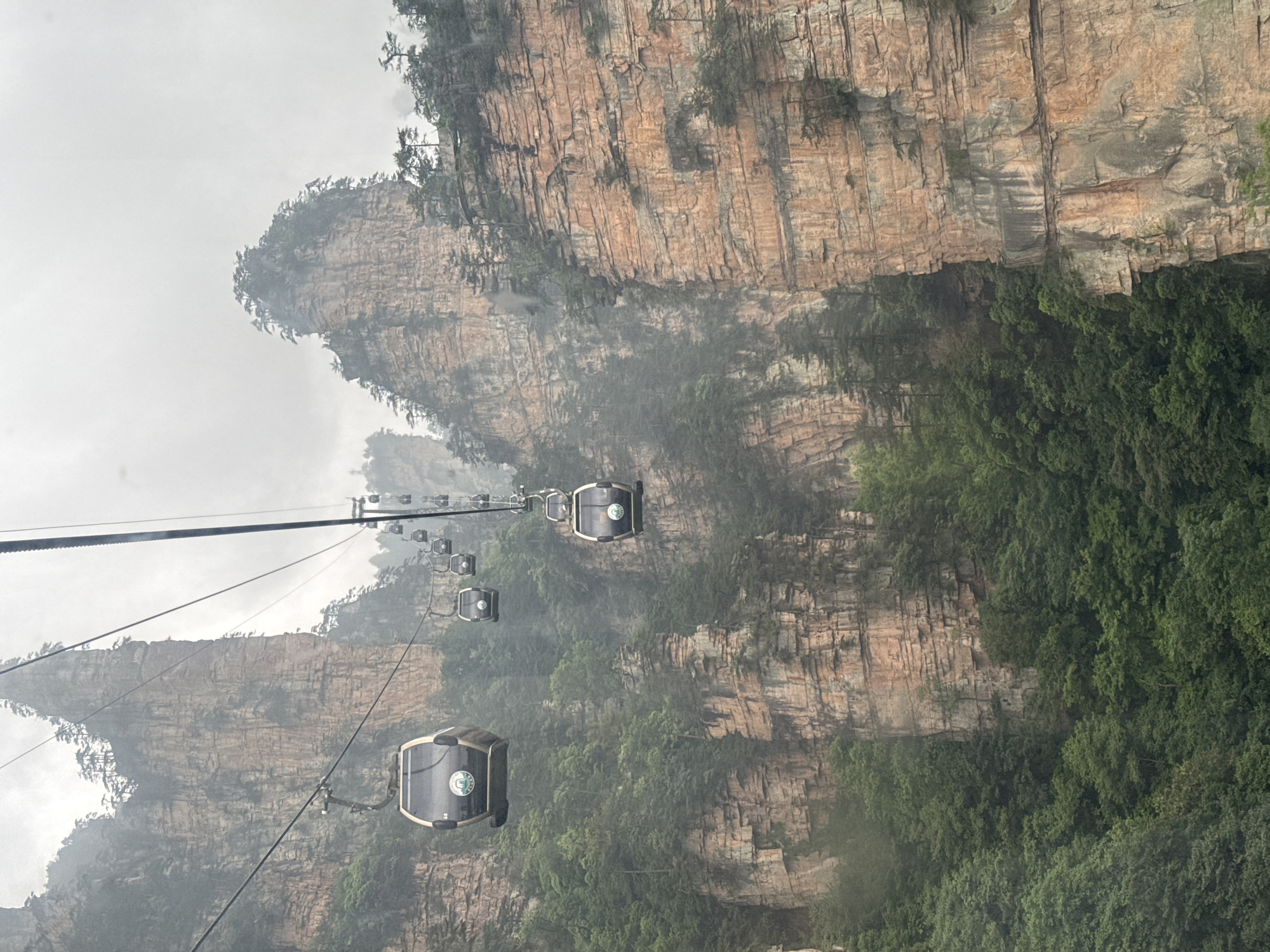 Cable cars operate through foggy mountains in Wulingyuan, China