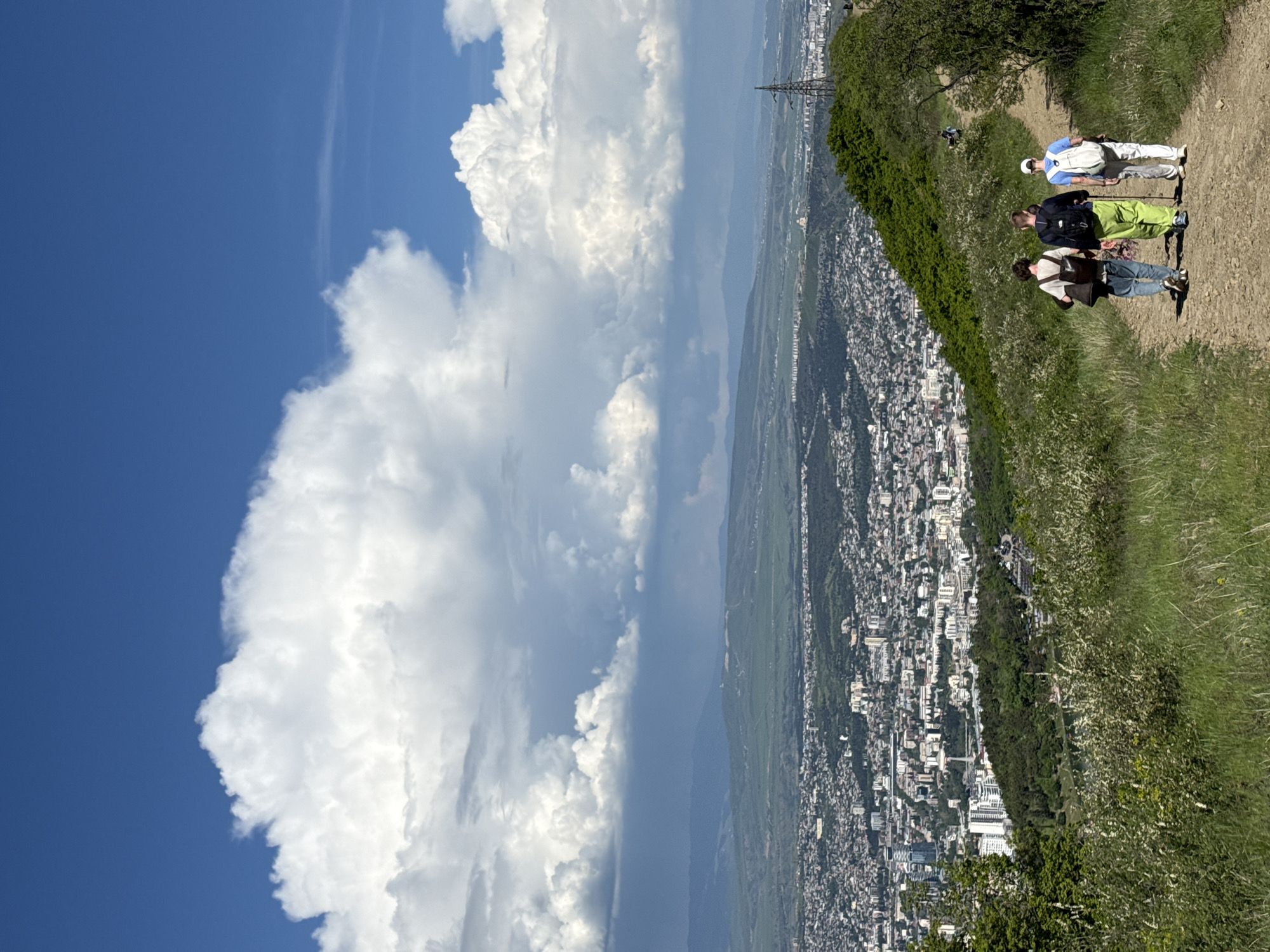 Hiker and dog explore Tbilisi hillside trails with city views