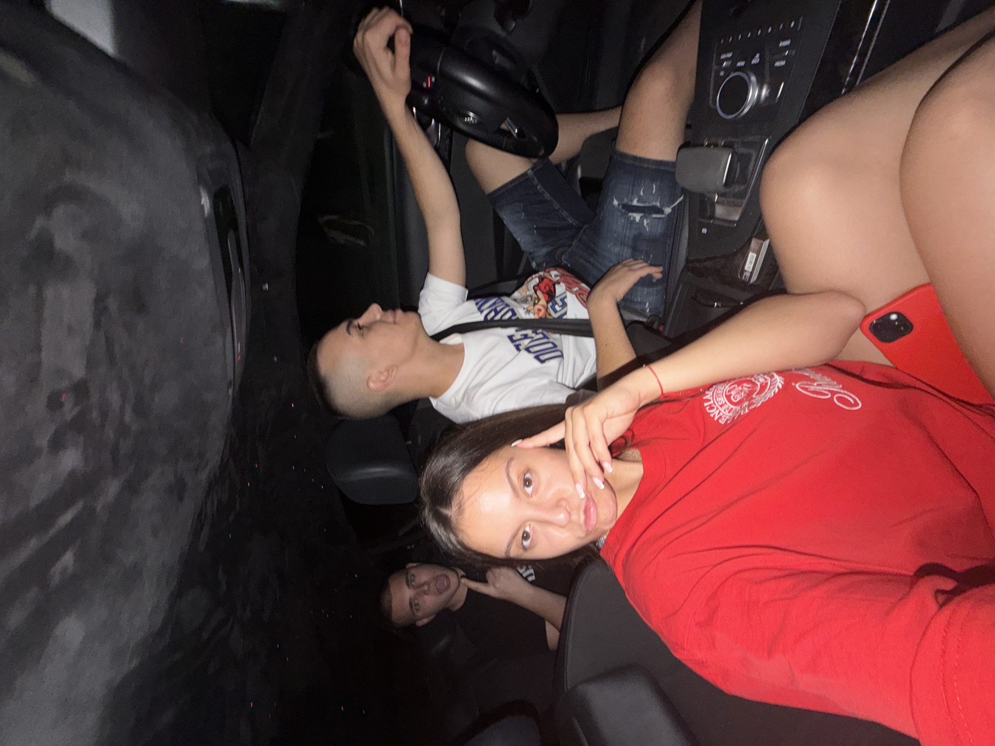 Young woman poses playfully in car at night in Ruse