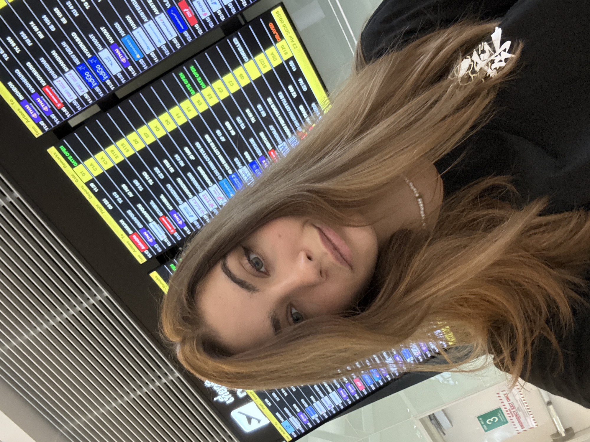Woman poses at airport departure board in Thailand