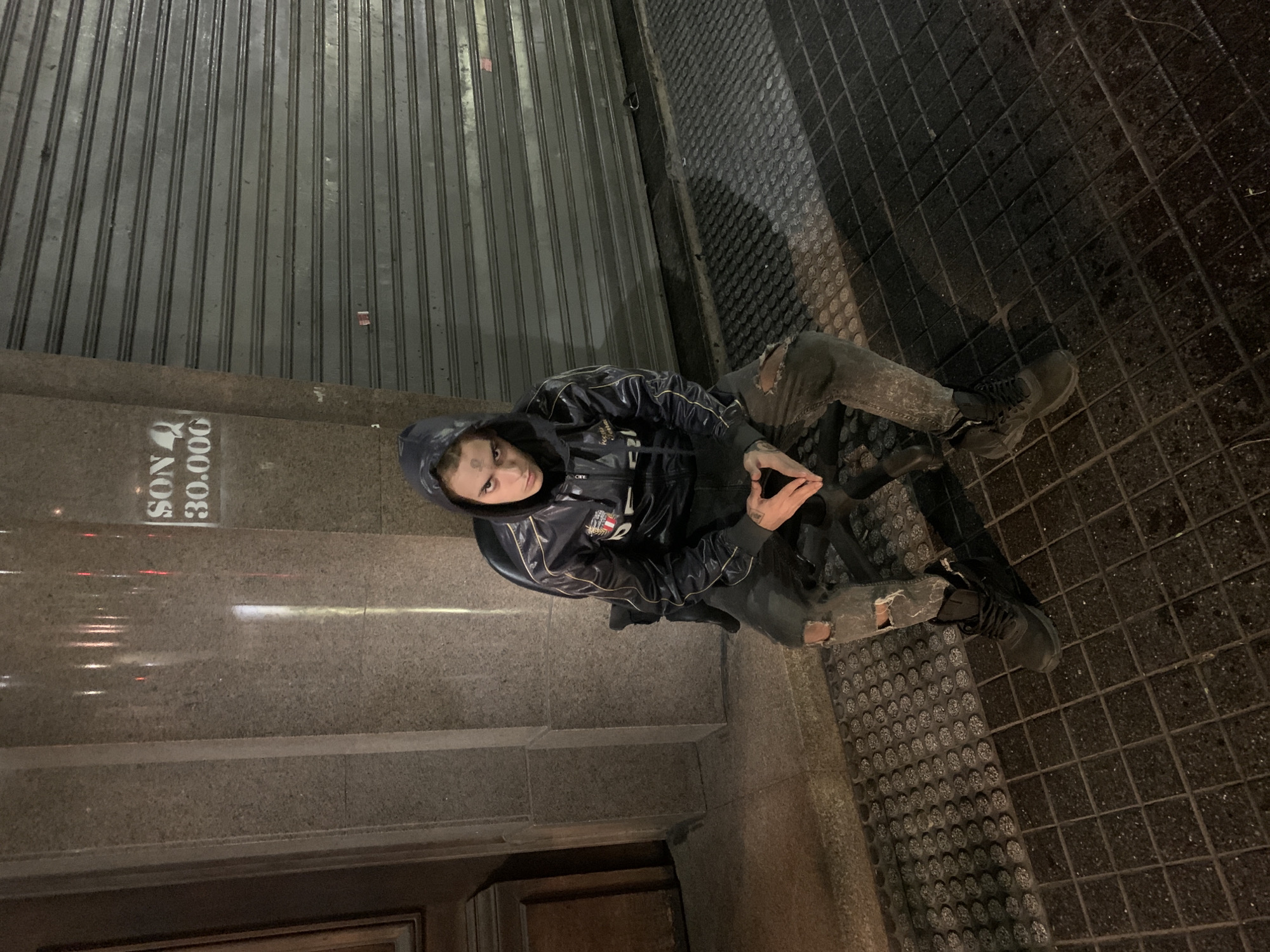 Person sits on Buenos Aires street near illuminated Obelisk