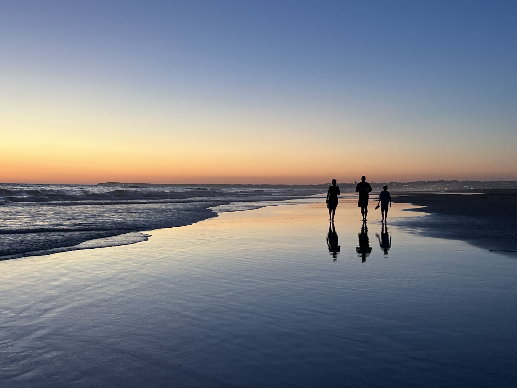 Dusk on Zahara beach, three silhouettes at the Atlantic shore