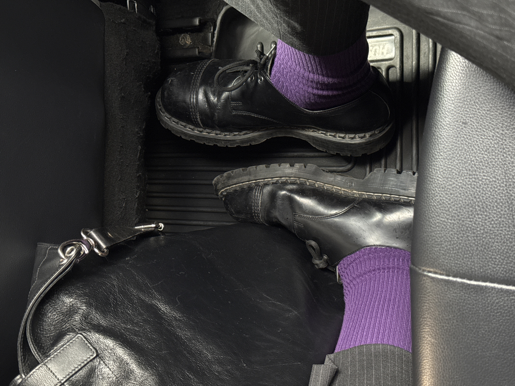 Person in pinstripe pants, purple socks photographed in NYC car
