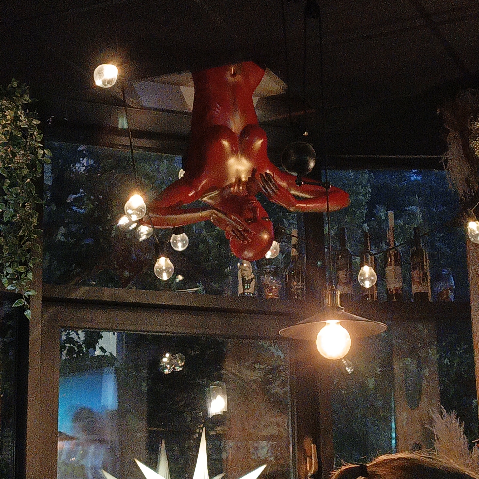 Giant red upside-down figure serves as an indoor chandelier