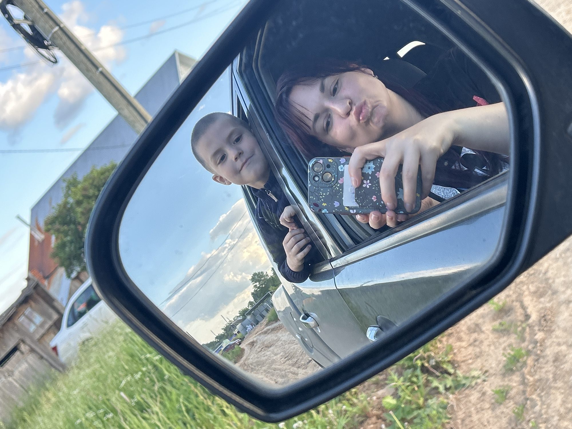 Woman and boy take leisurely car trip through Russian village