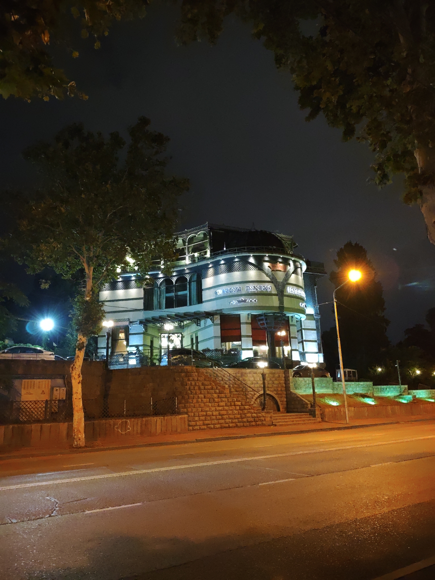 Nighttime stroll along Tbilisi's Mtkvari River, city lights reflected