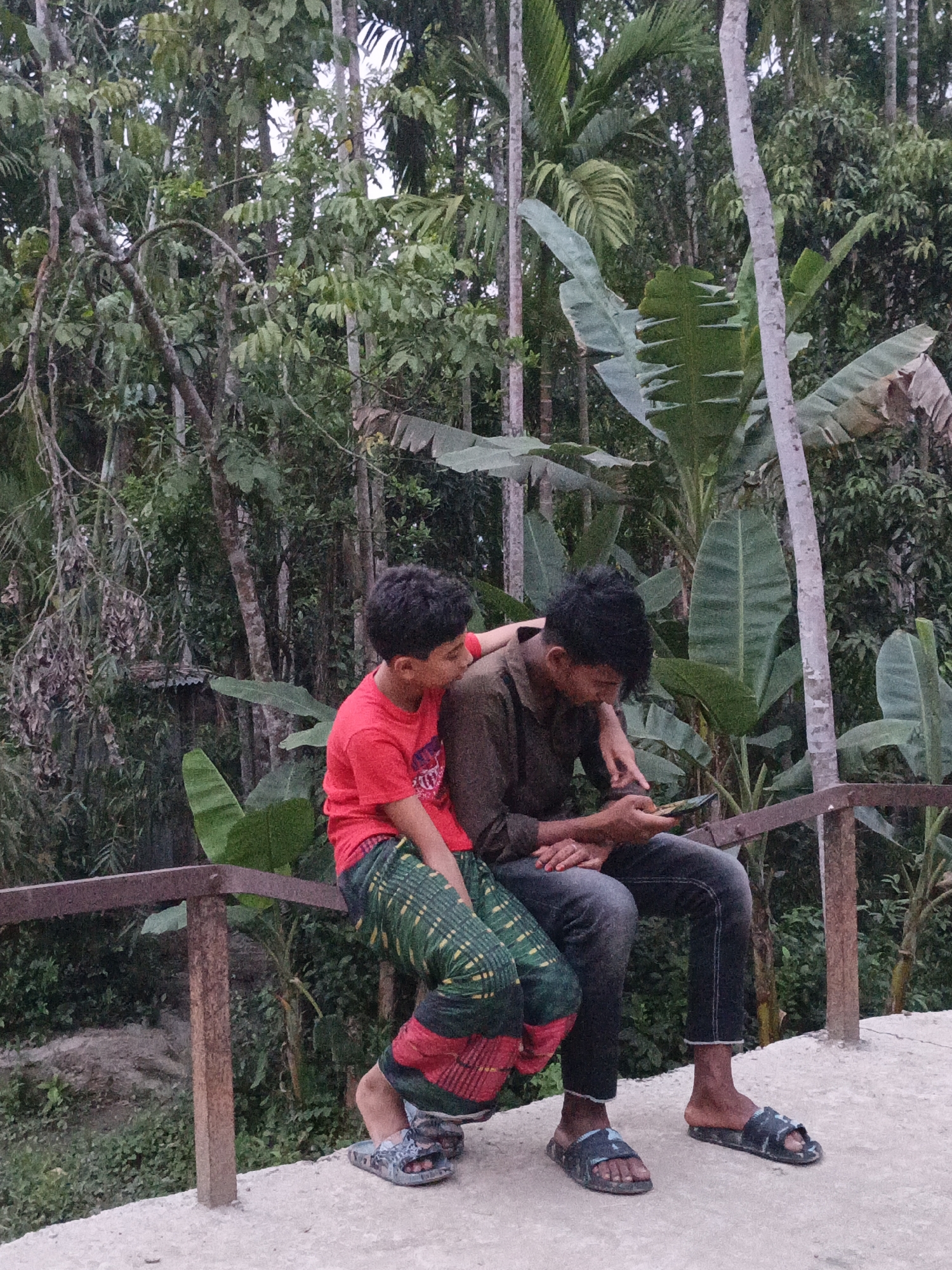 Two people rest by verdant waterside landscape in Bangladesh