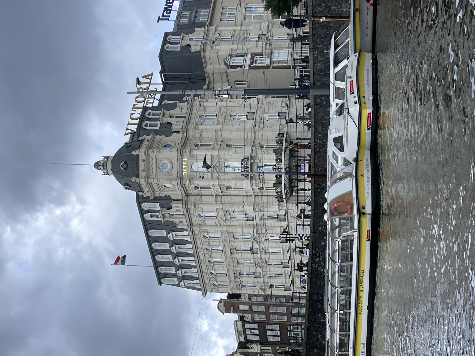 Tourist documents Amsterdam canal tour on overcast morning