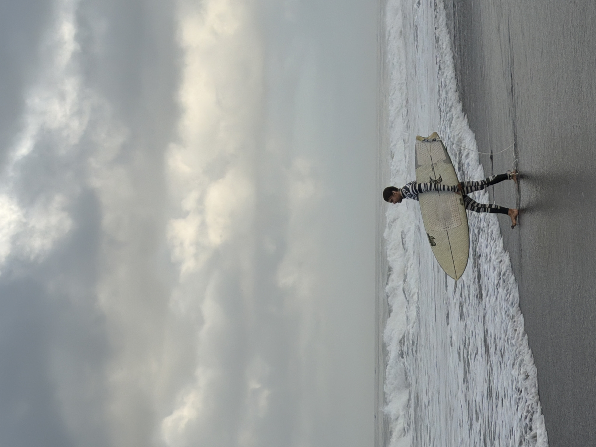 Late night surfer spotted on overcast Kediri beach