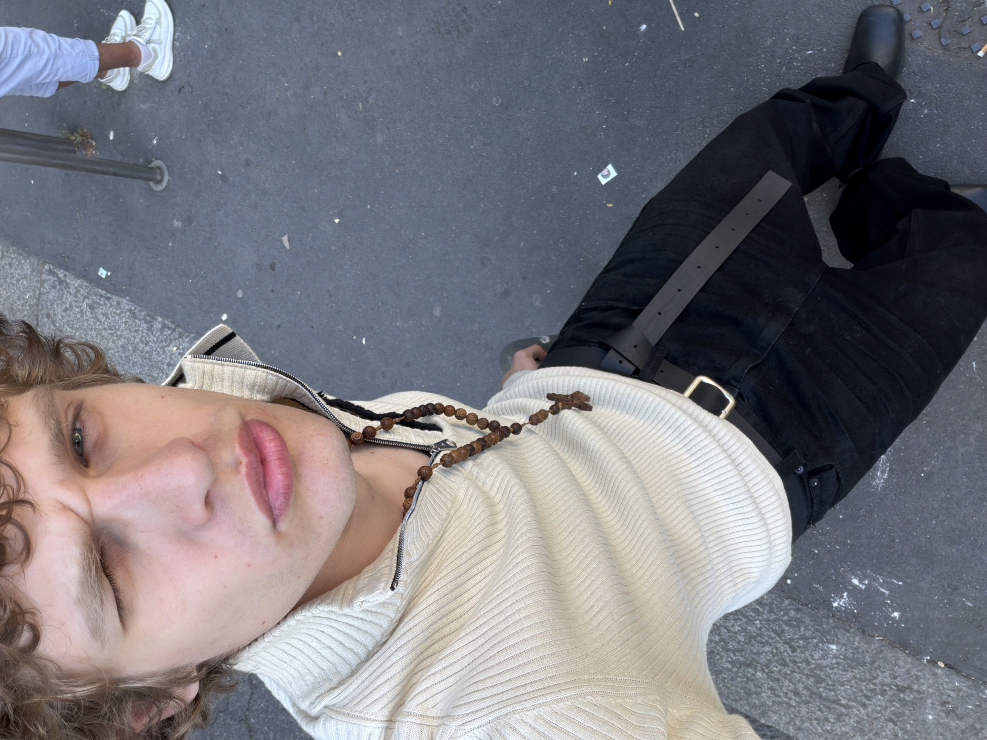 Person in cross necklace photographed from above in Milan