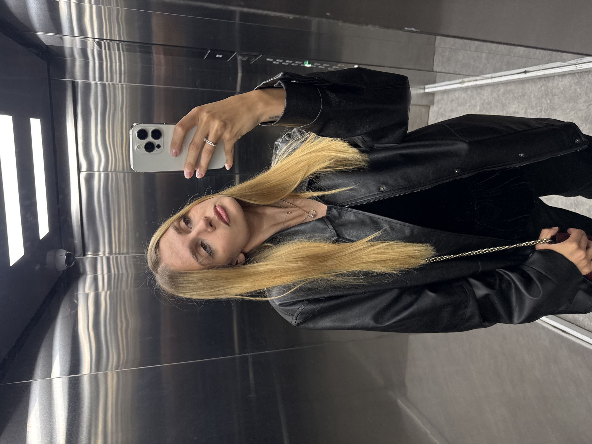 Woman takes selfie in stainless steel elevator