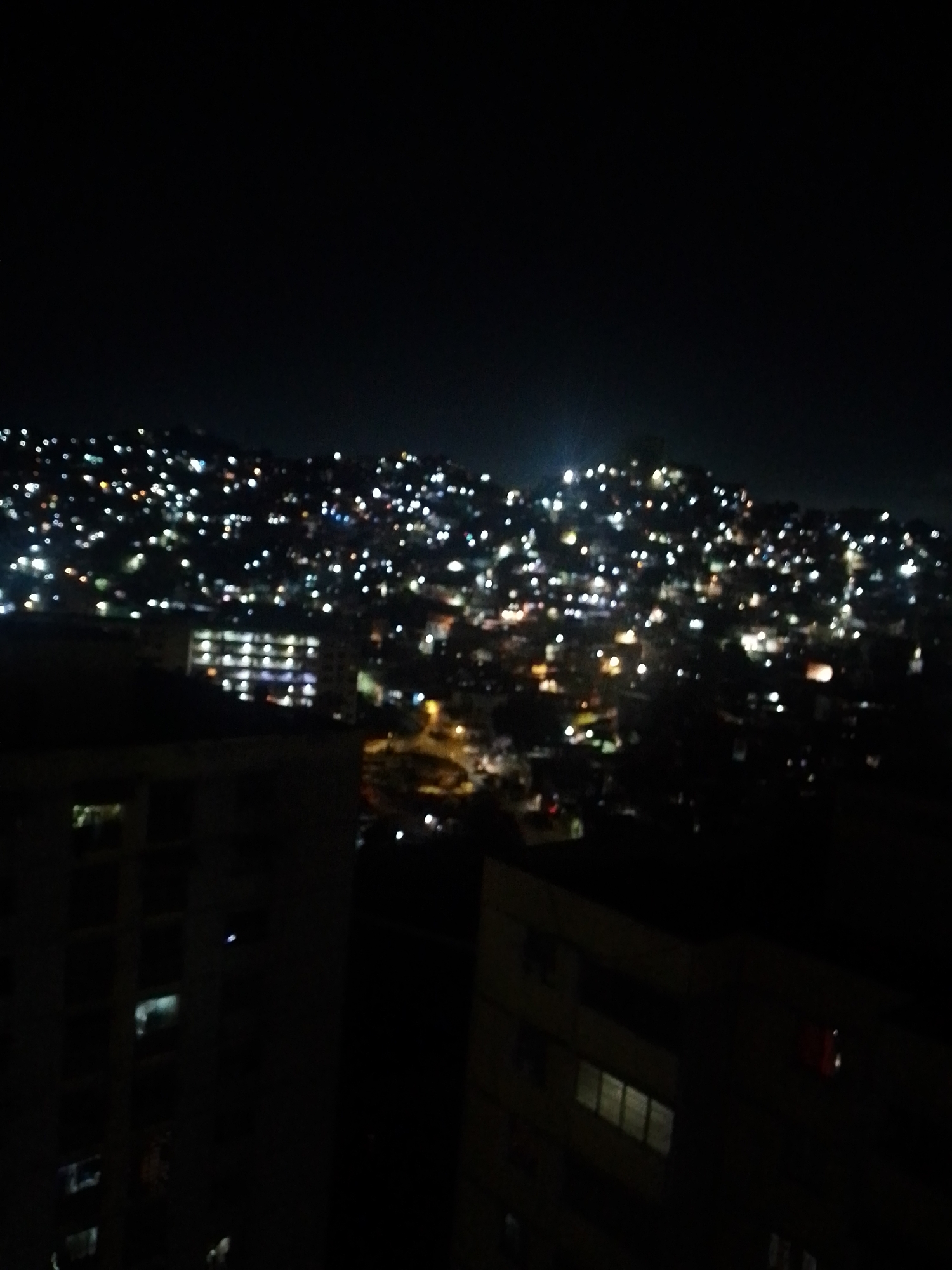 Caracas hillside neighborhoods glow across a dense nighttime skyline