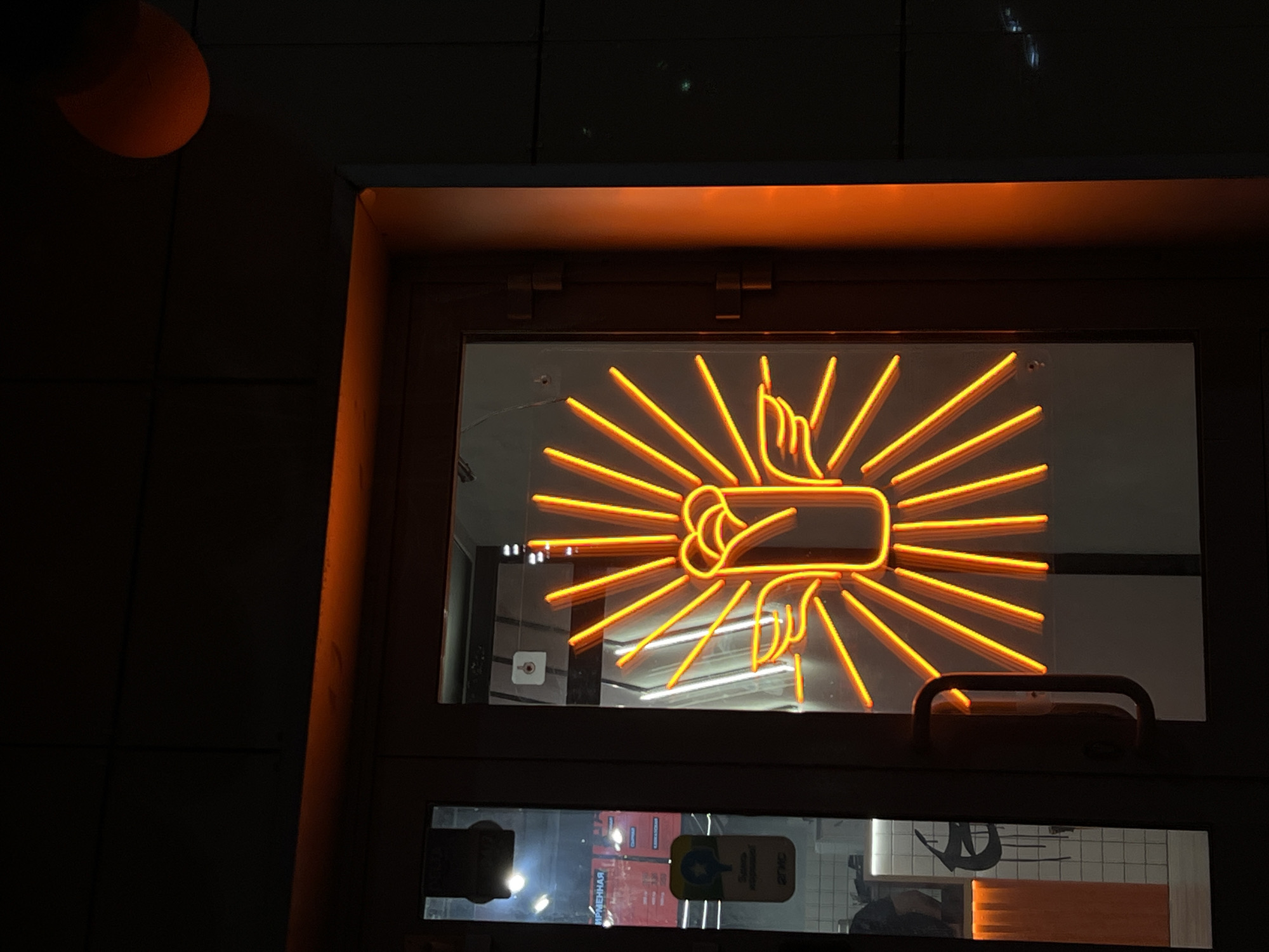 Orange neon fig sign gesture displayed in Kazan window