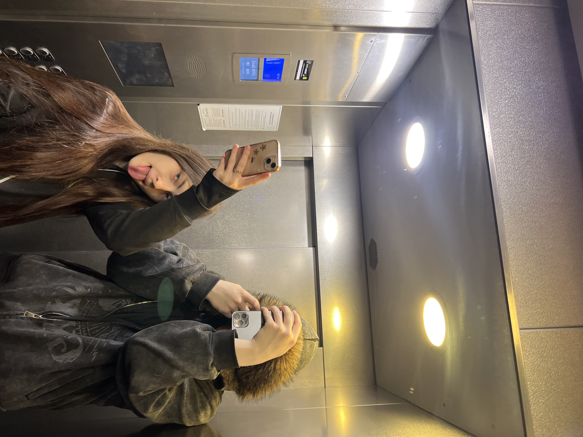 Two people take playful selfie in elevator
