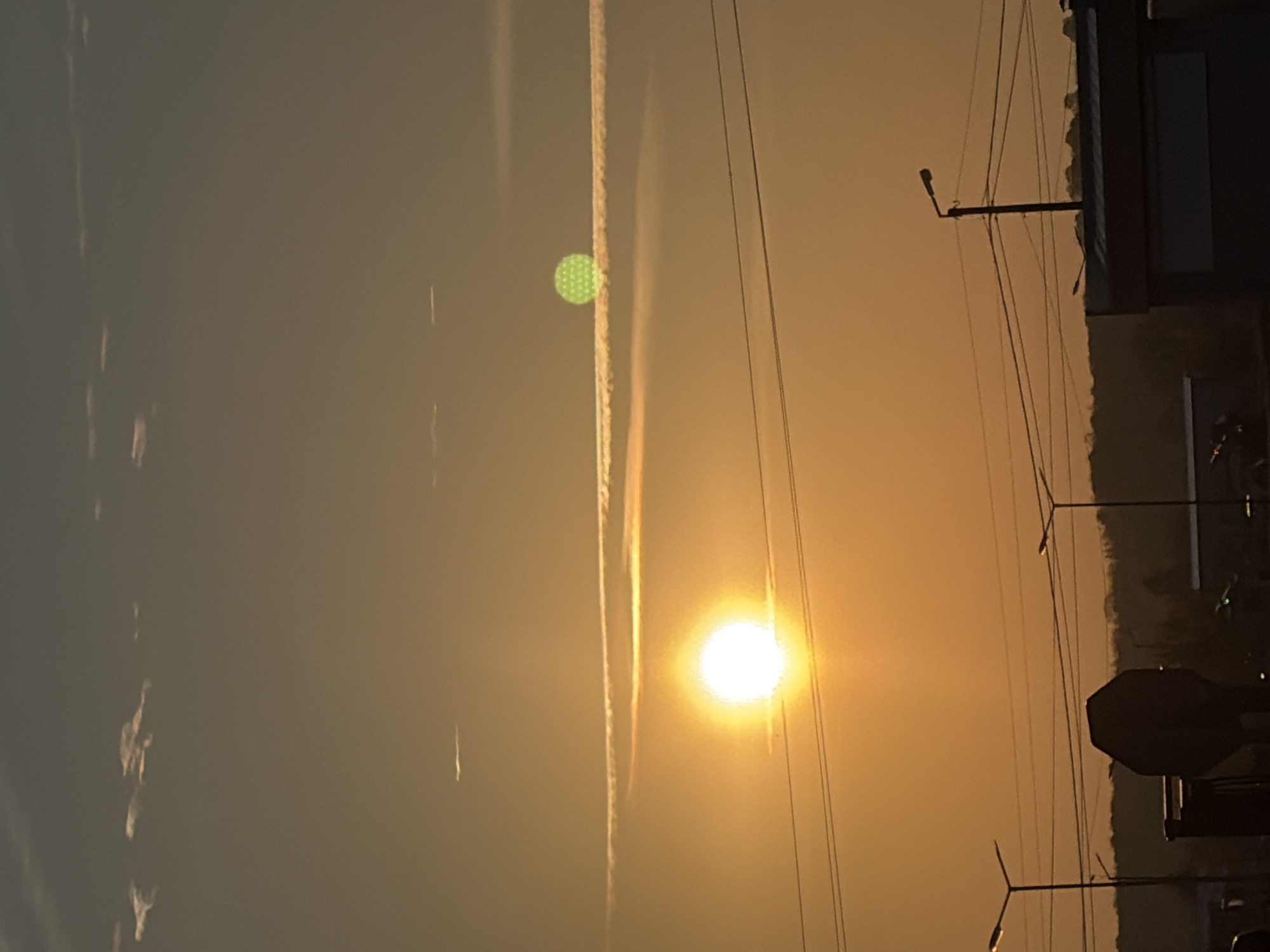 Urban sunrise captured with vapor trails and power lines