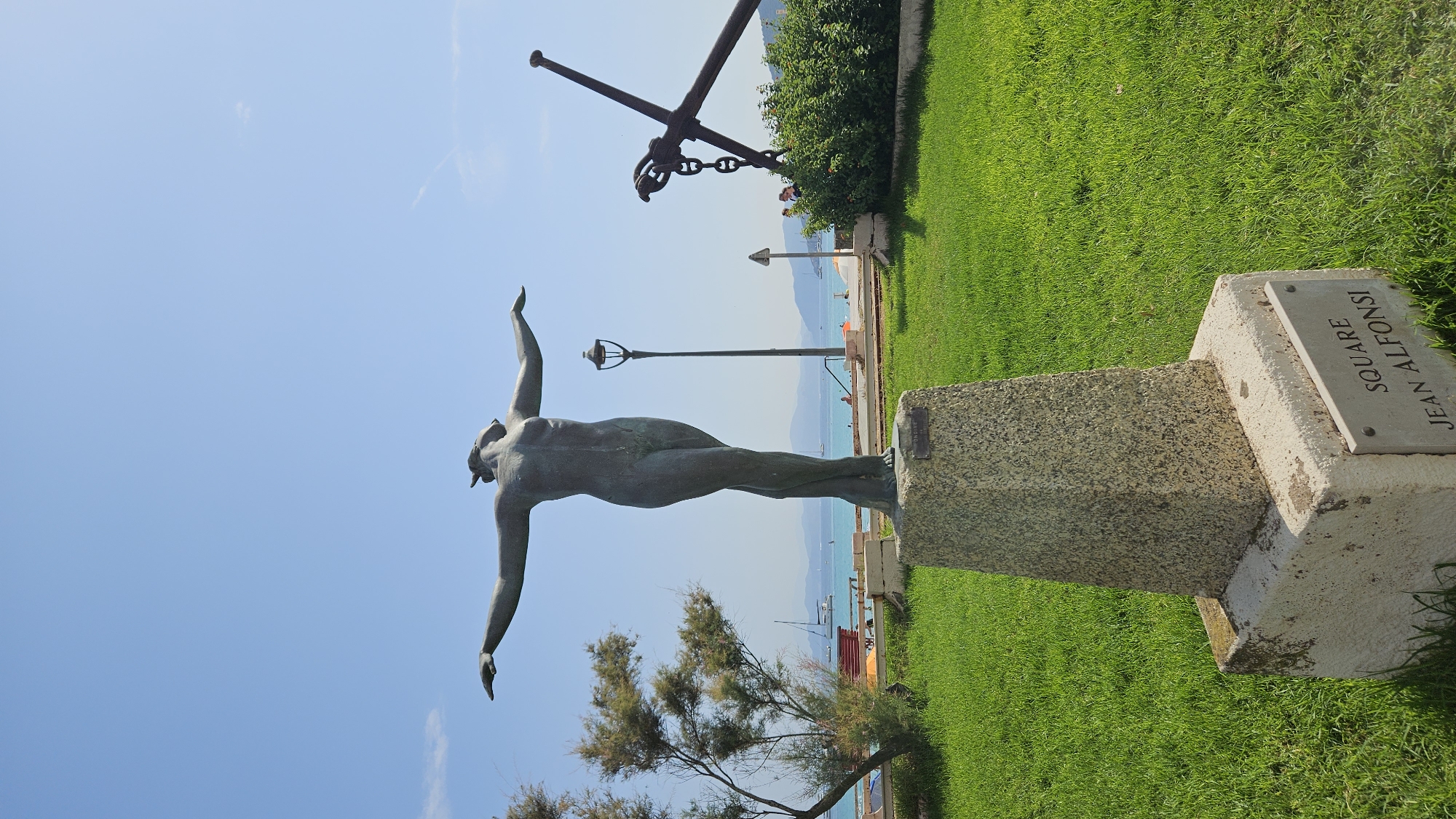 Bronze figure and rusted anchor mark L'Île-Rousse's seafront