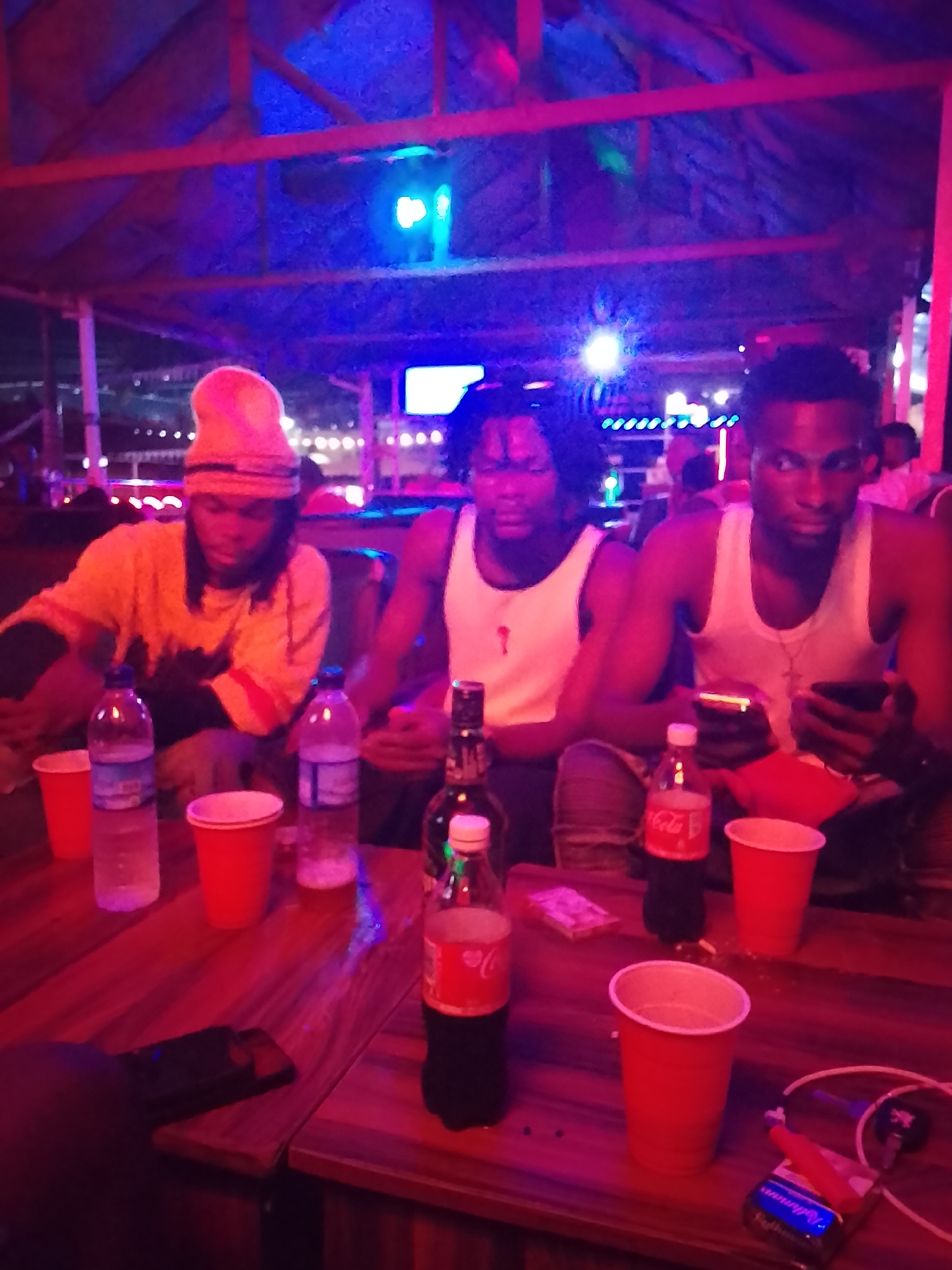 Three men gather at indoor table with beverages