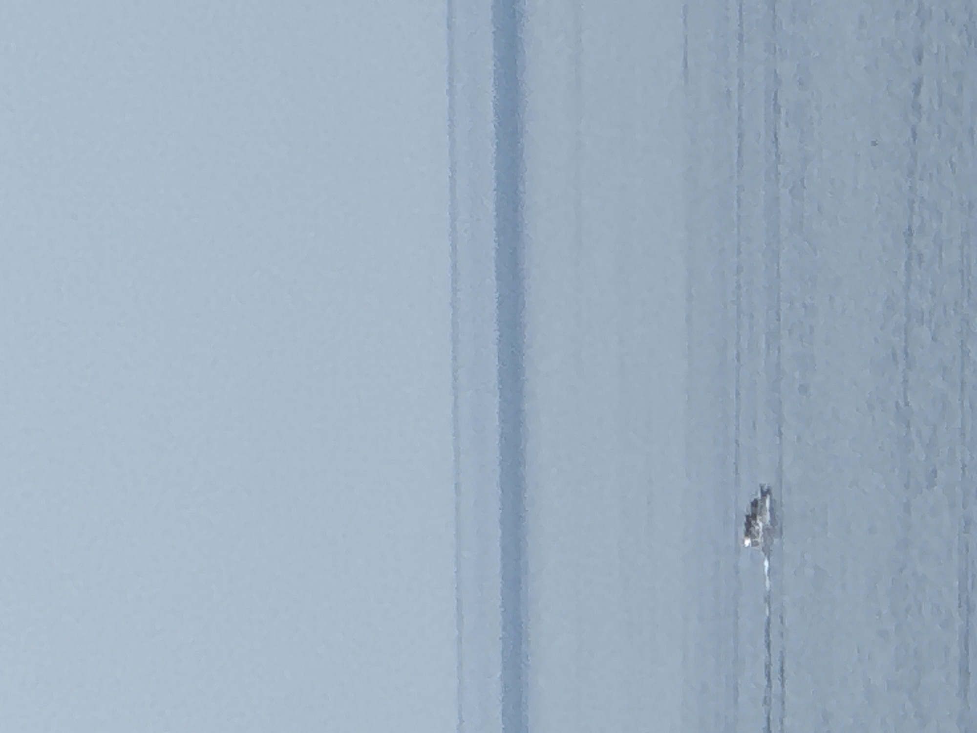 Small boat cuts through hazy morning waters off Boreti