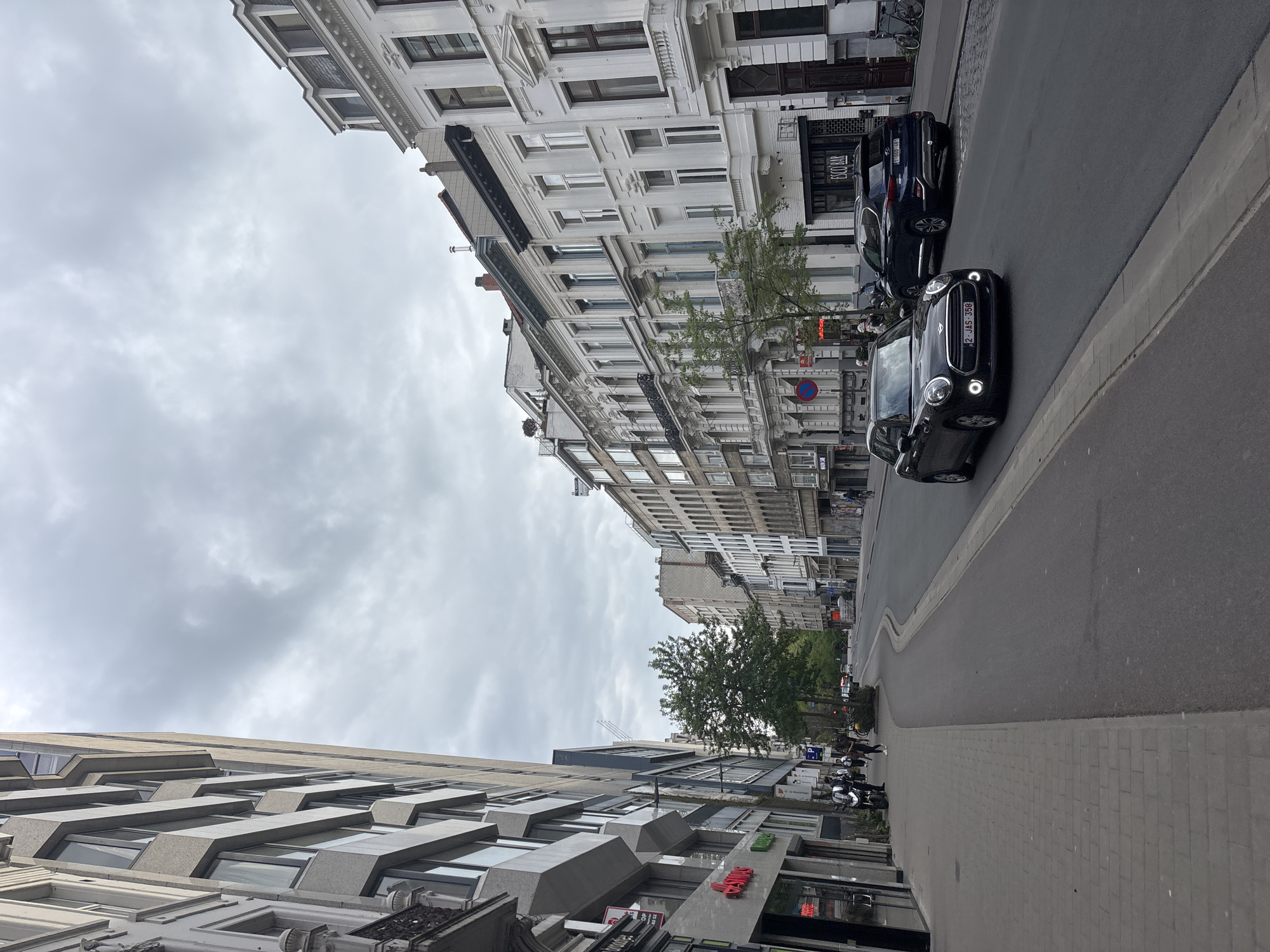 Person in leather jacket walks past parked Vespa in Antwerp