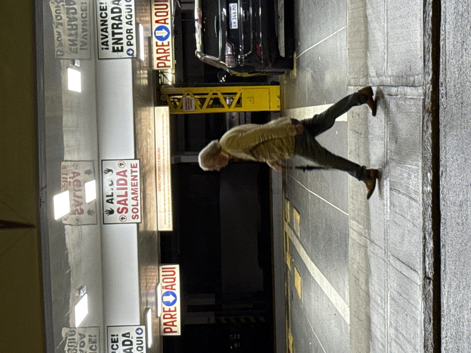 Elderly man walks toward wall in Buenos Aires parking garage