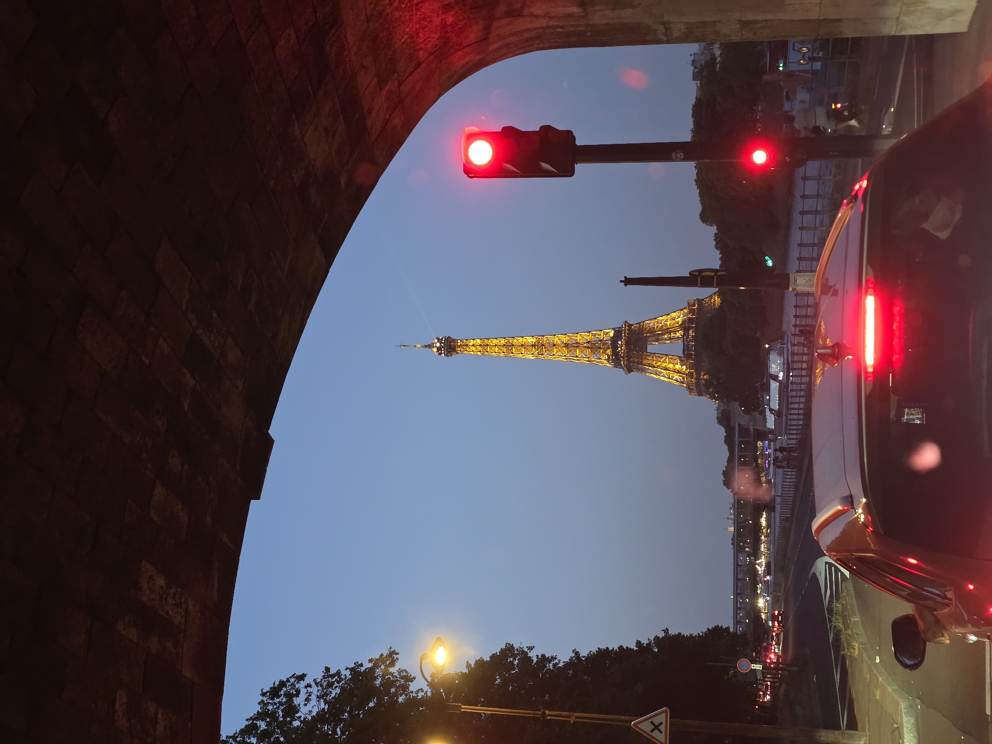 Eiffel Tower glowing at dusk, framed through a stone archway