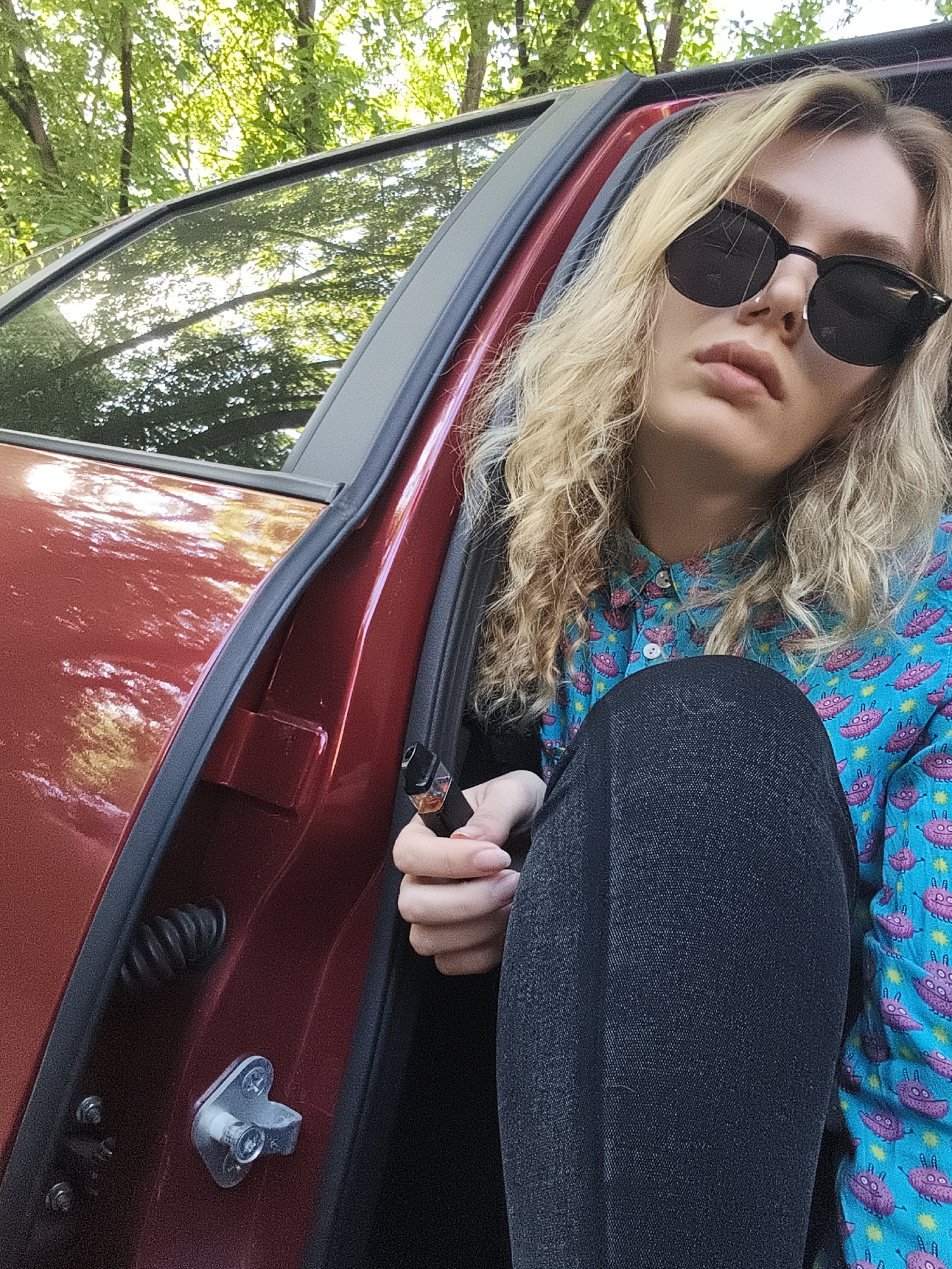 Person in alien shirt sits in red car, Izhevsk