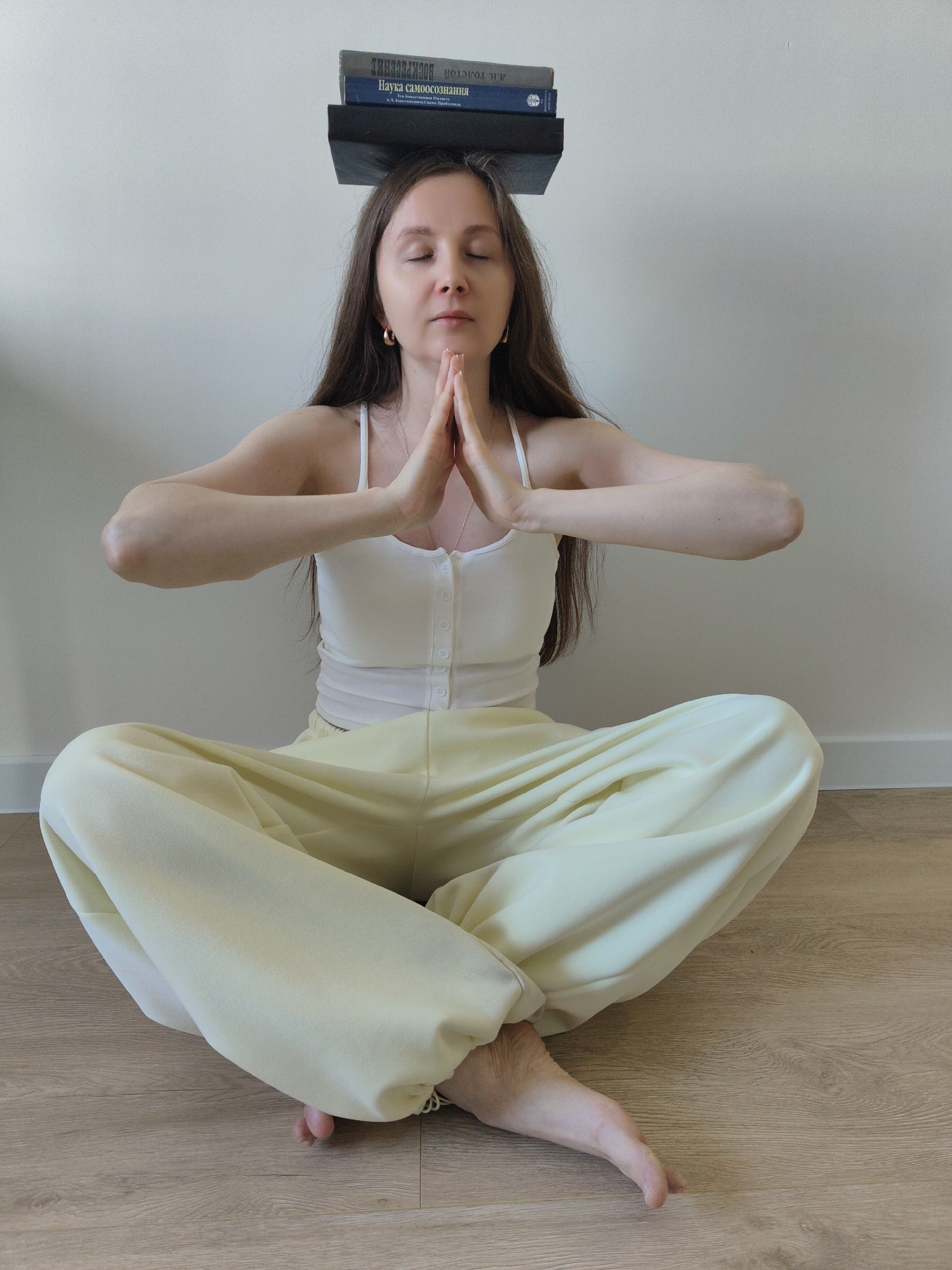 Woman meditates while balancing Russian self-realization book on head