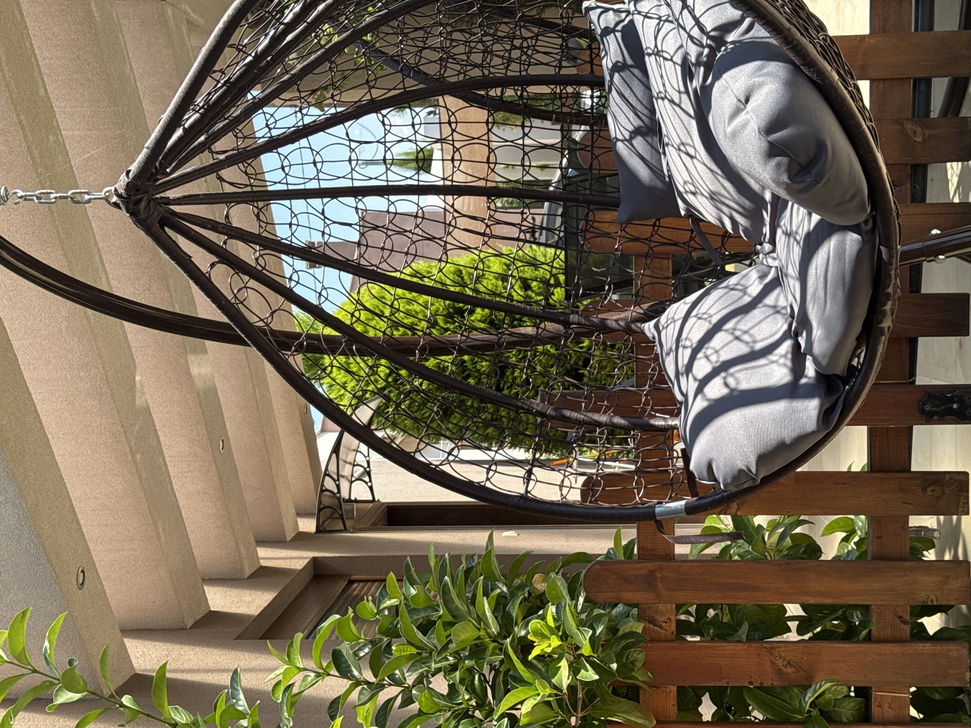 Hanging egg chair on a patio with garden backdrop