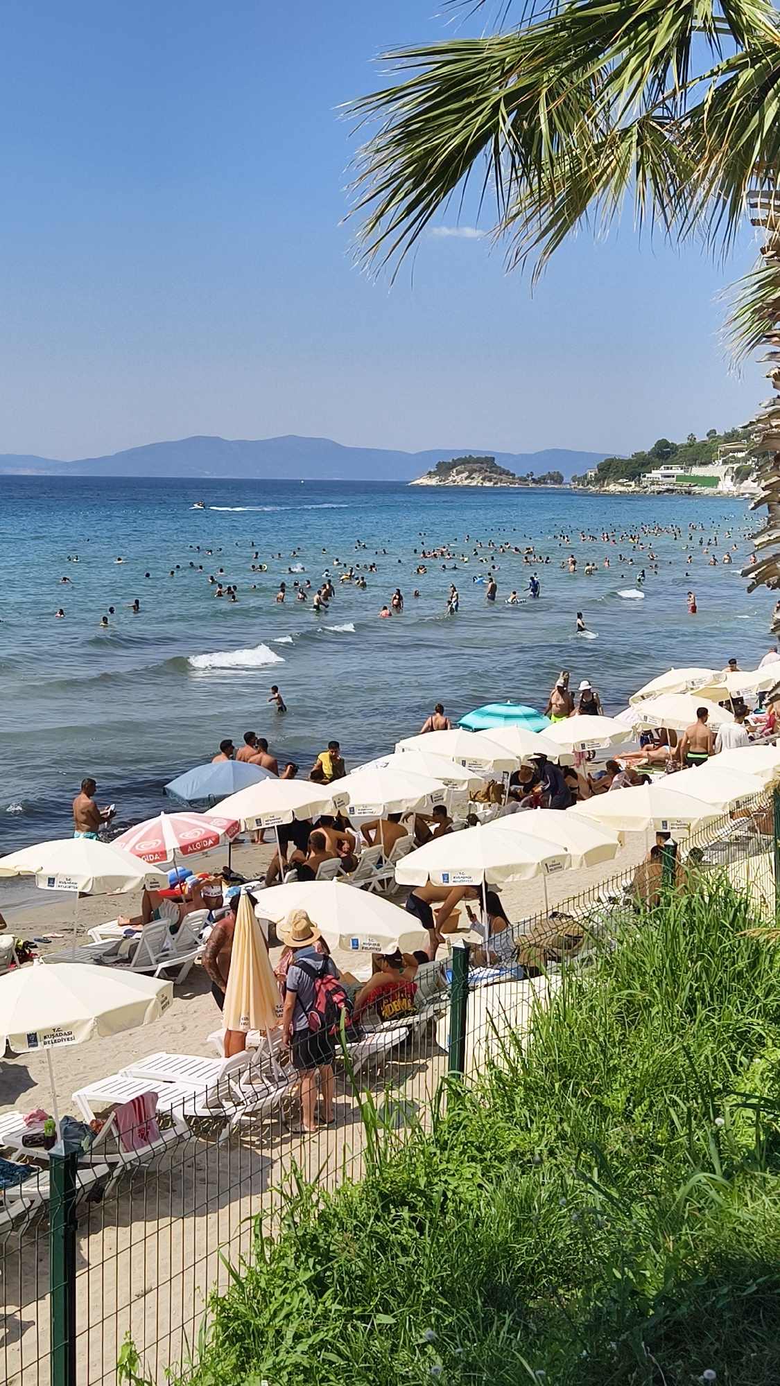 Busy Aegean beach day in Kuşadası with a costumed aside