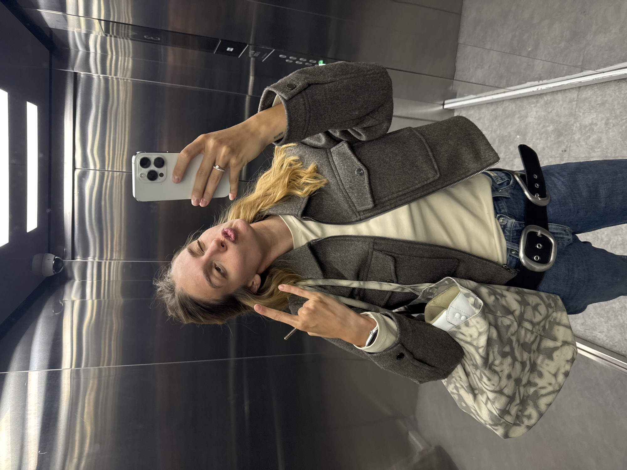 Woman takes selfie in elevator with white smartphone