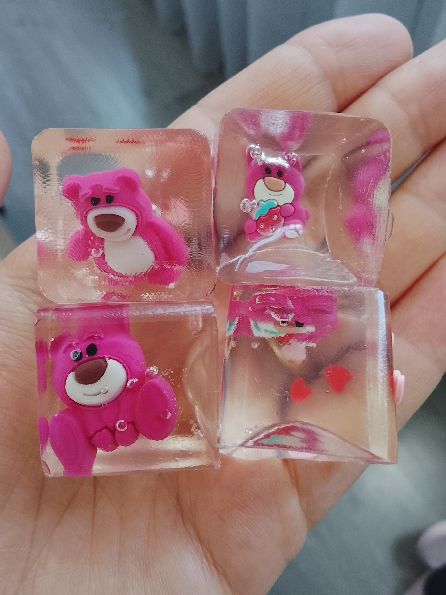 Person holds four cubes containing pink Toy Story bear figurines