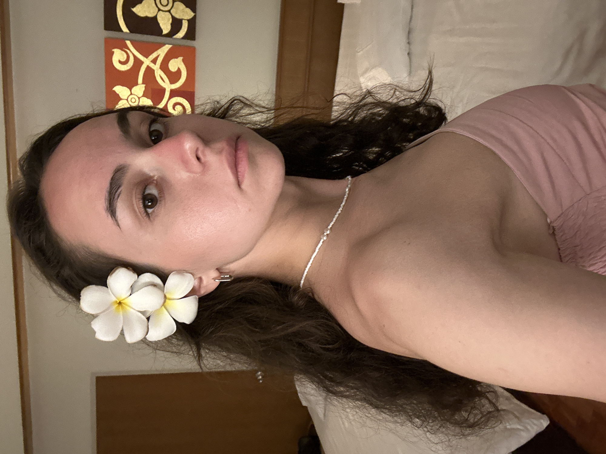 Woman poses with plumeria flowers in Pattaya hotel room