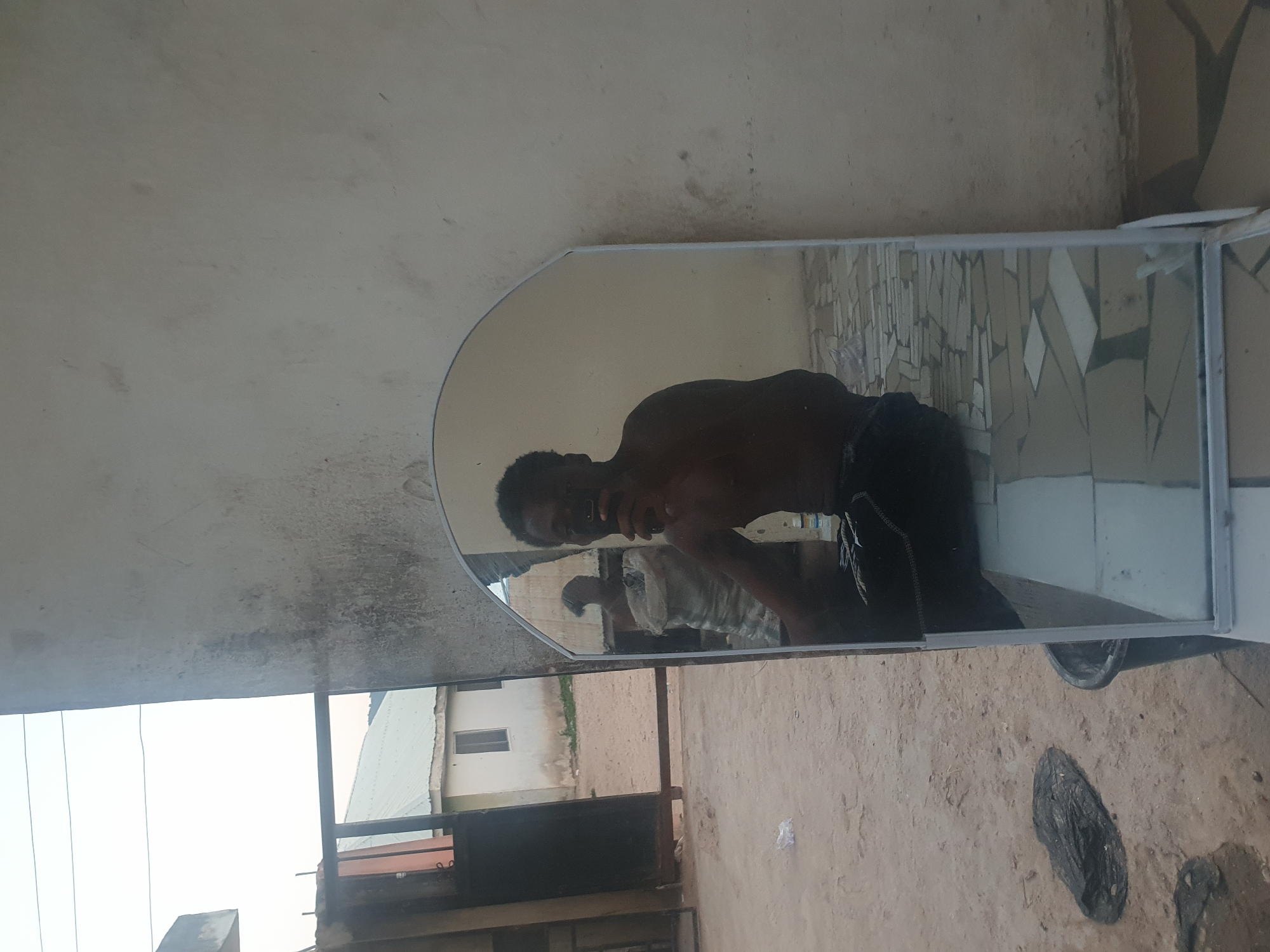 Man takes outdoor mirror selfies in Lokoja courtyard