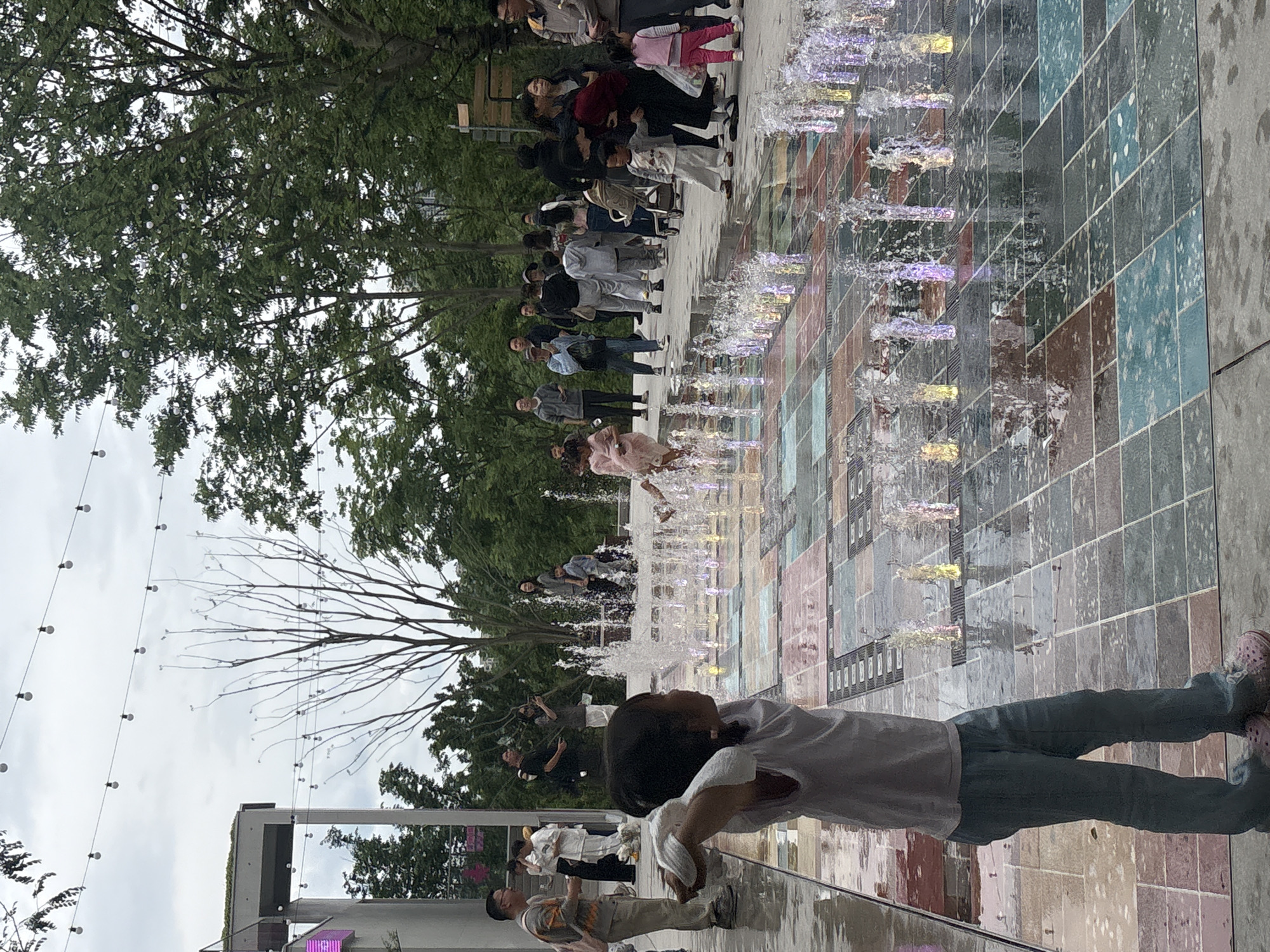 Child stands by fountain in Liangjiang street scene