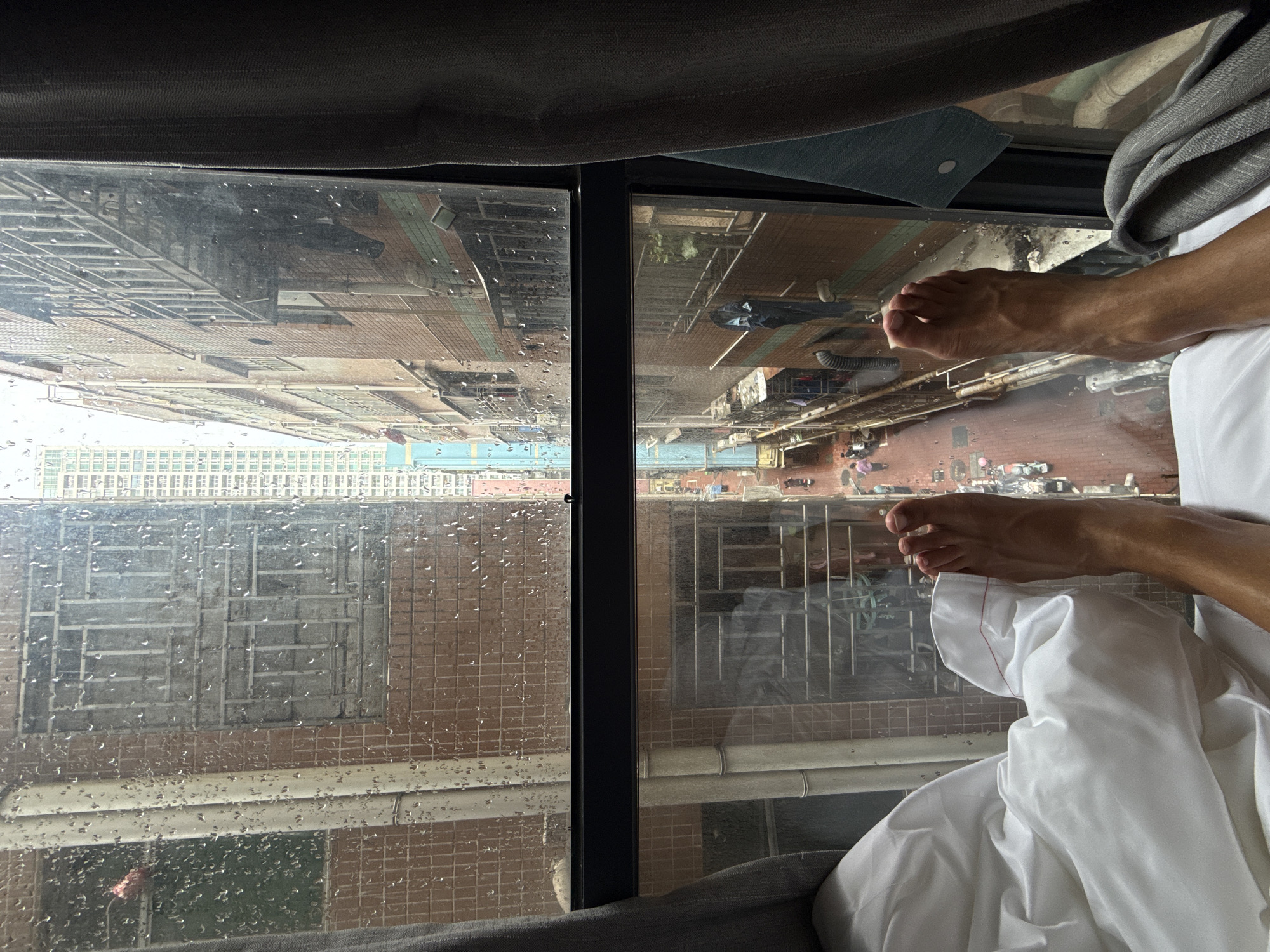 Person rests by rainy window in Futian high-rise