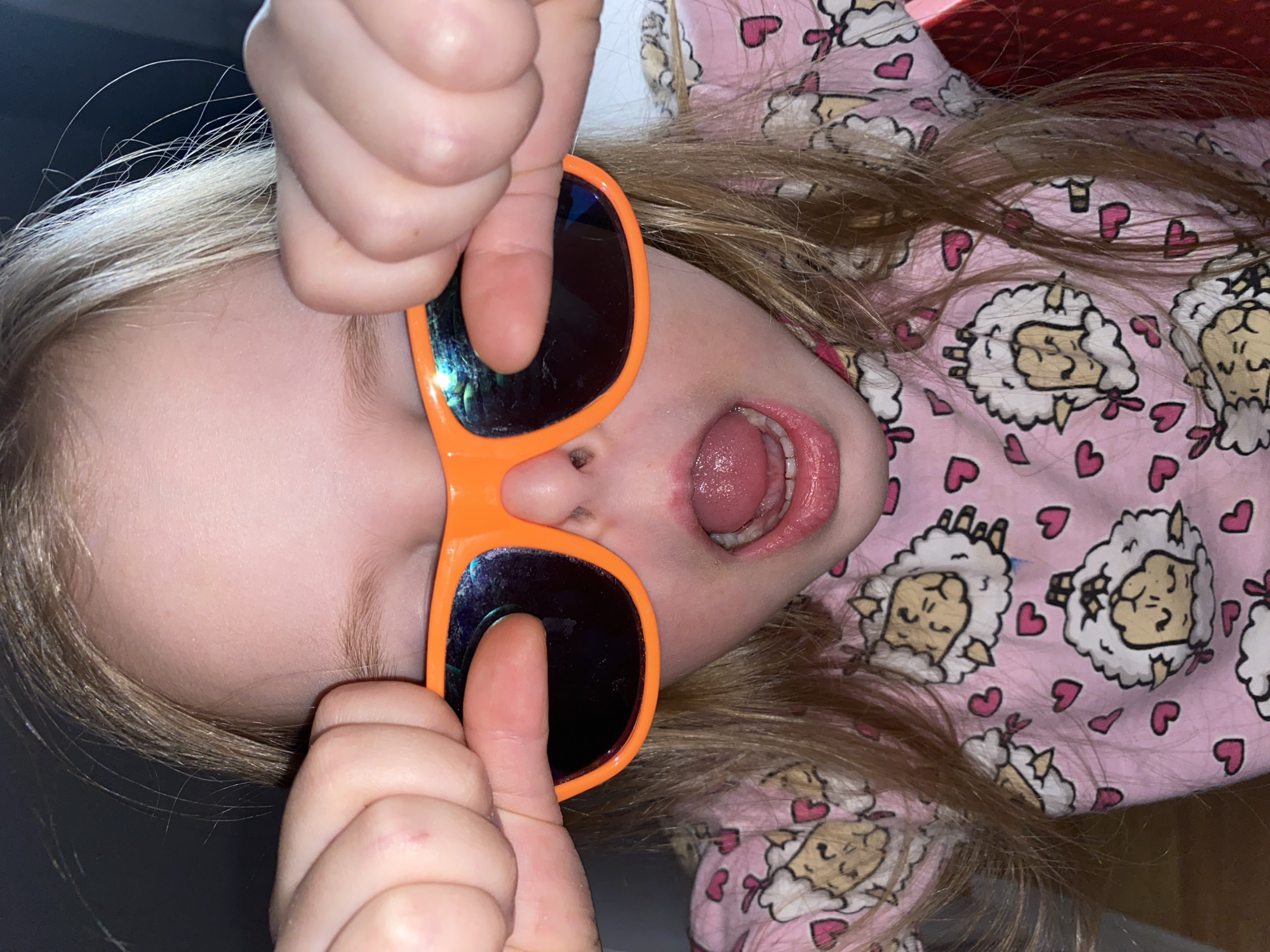 Child plays with orange sunglasses during sunset in Votkinsk