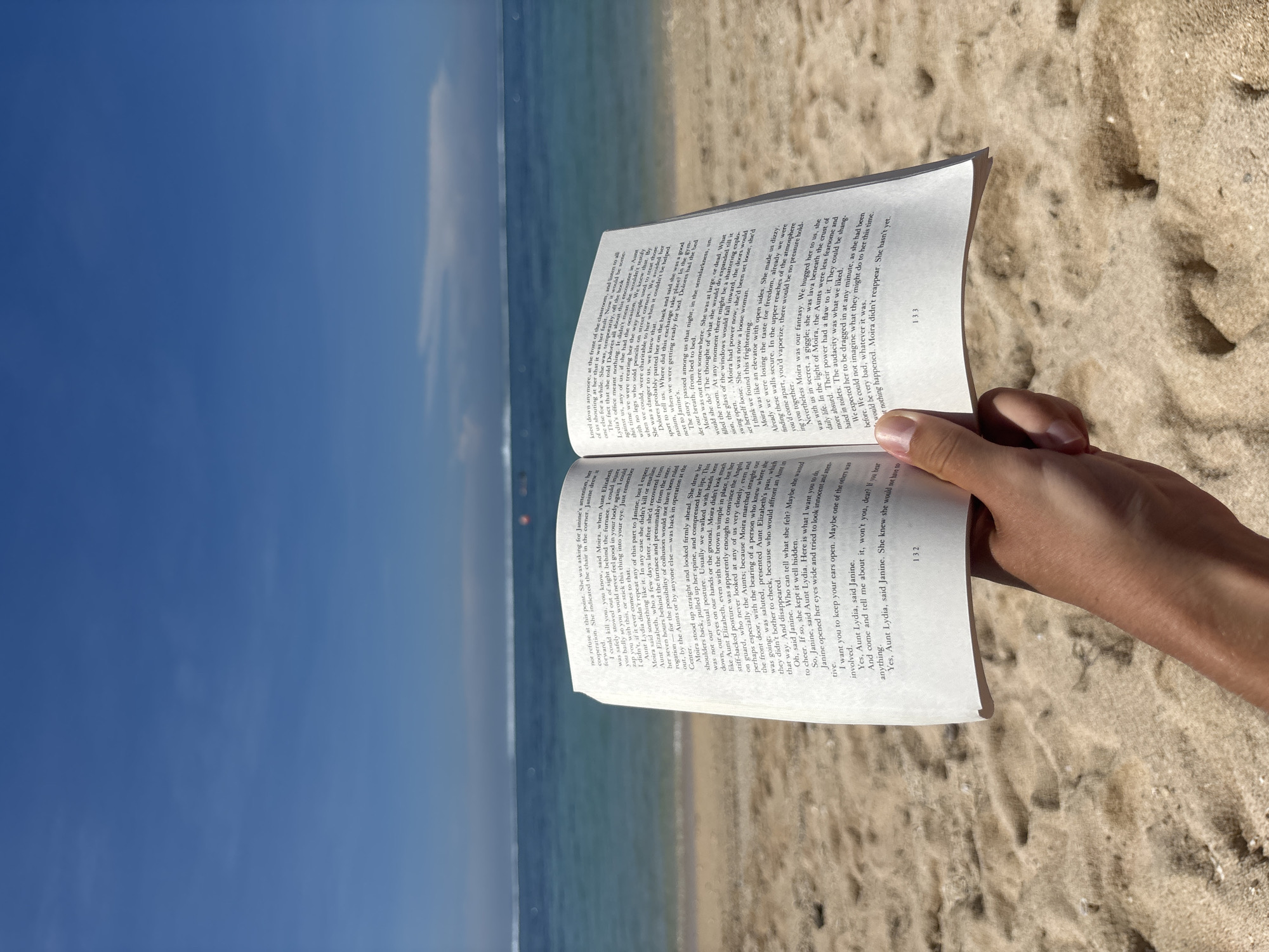 Beachgoer reads Handmaid's Tale at Kuta Selatan Indonesia beach