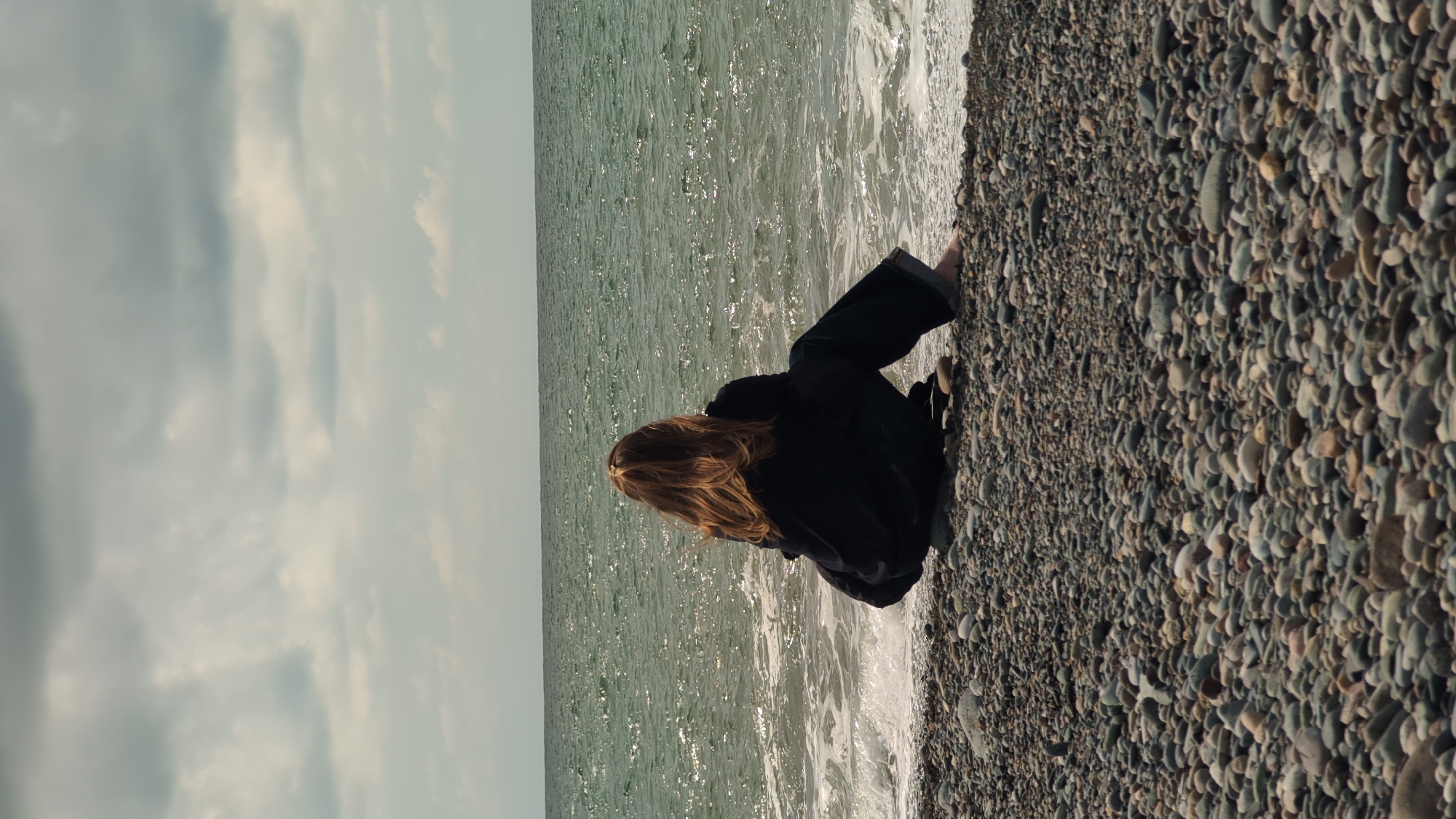 Person spends quiet moments on Kobuleti beach using smartphone