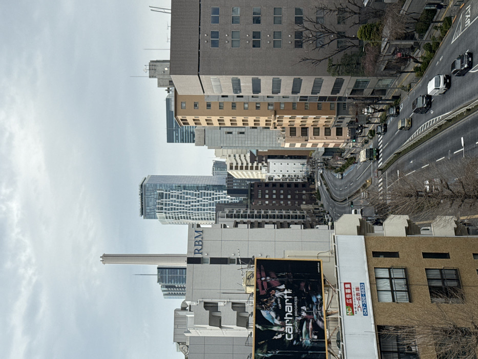 Commercial jet flies over bustling Shibuya under overcast morning sky