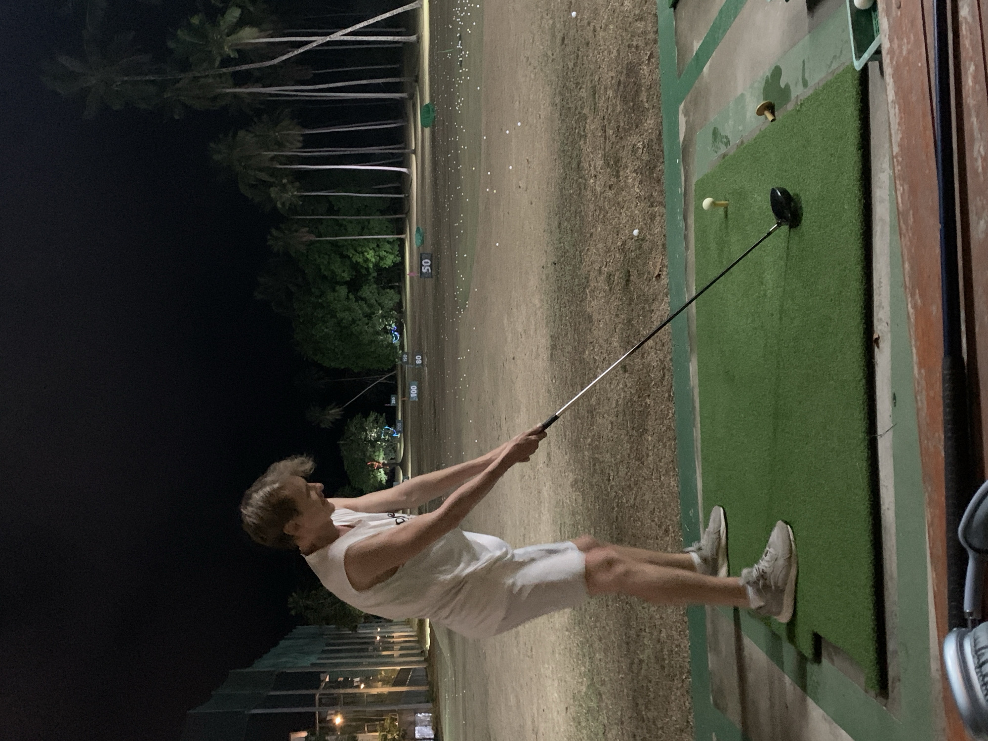 Golfer practices at night driving range in Thailand
