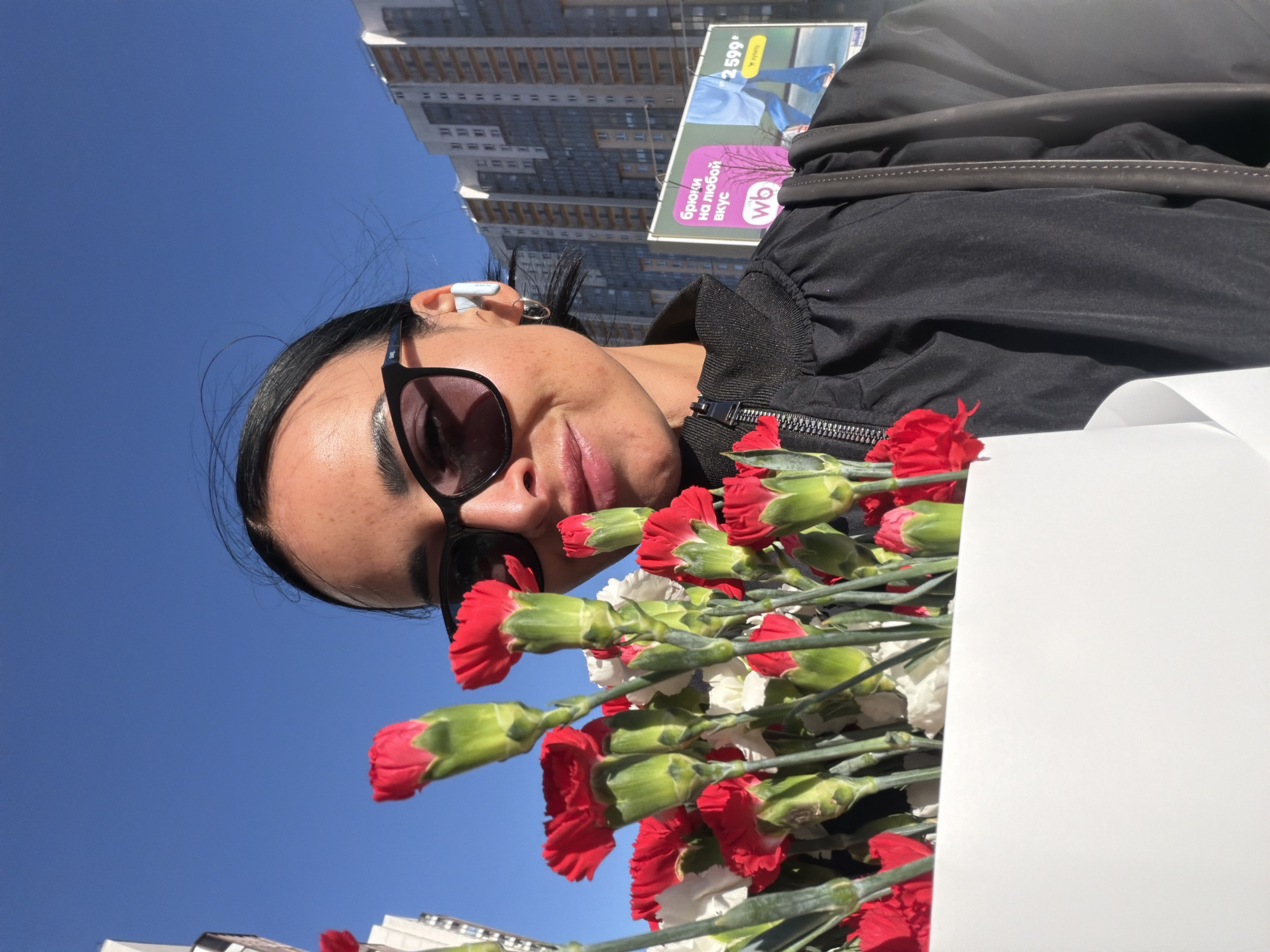Woman records selfie with flowers on Saint Petersburg street