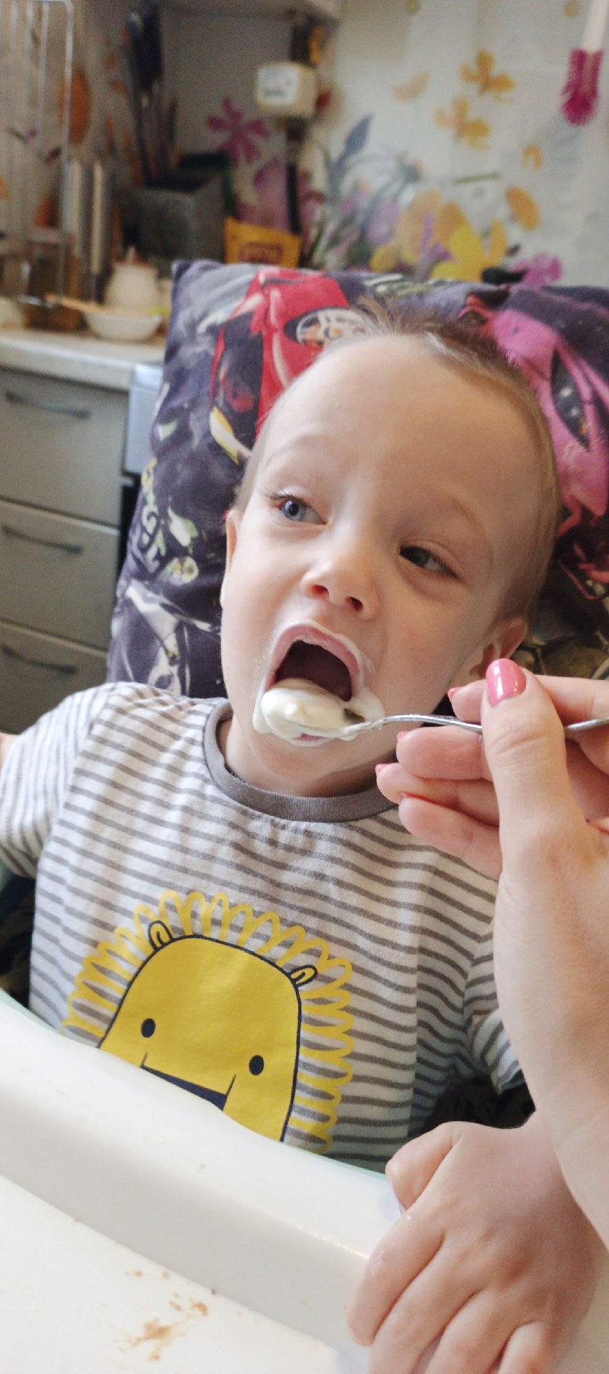 Adult feeds toddler at home in Chaikovsky, Russia
