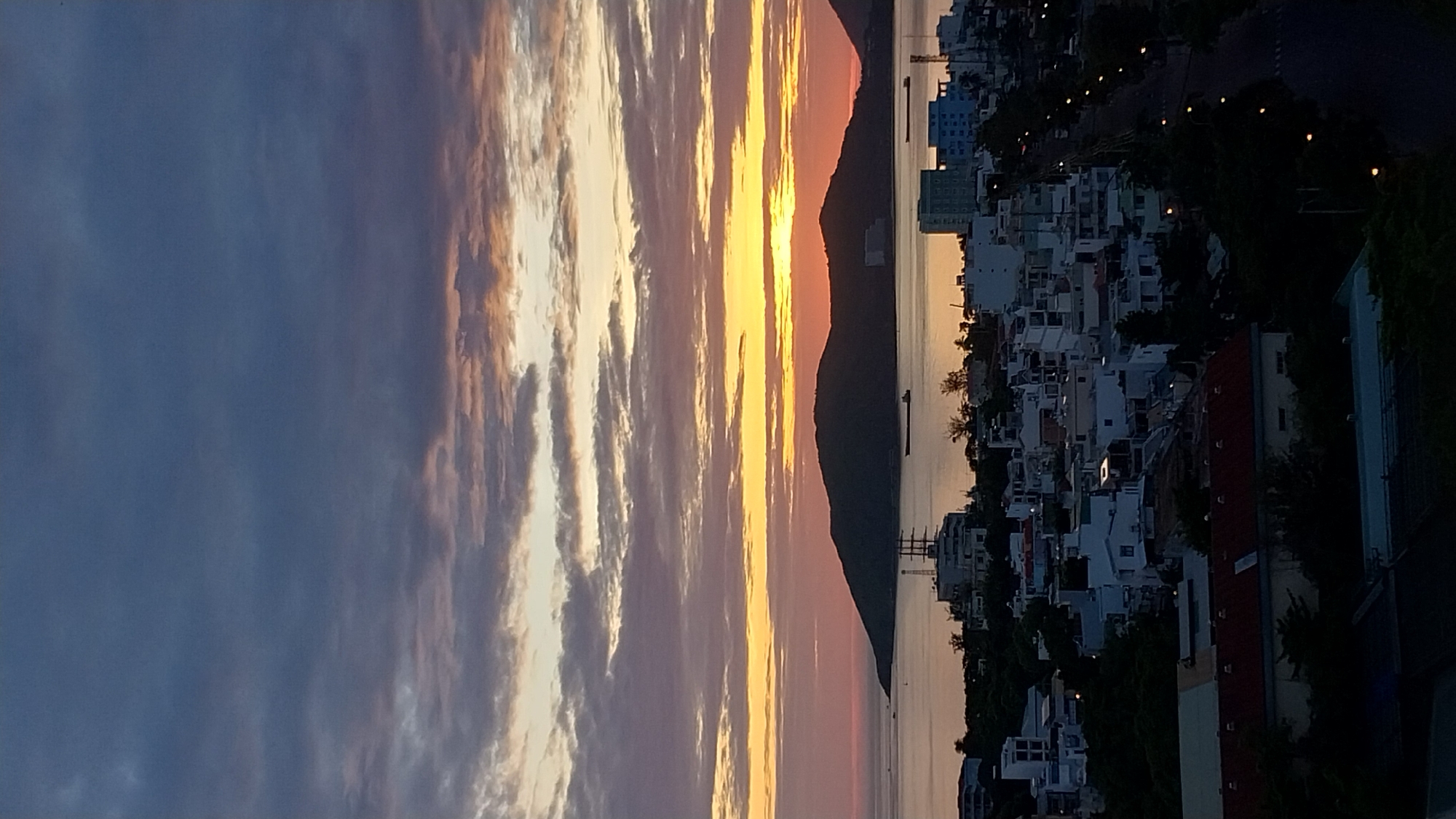 Coastal city sunset, sky shifting from blue to orange