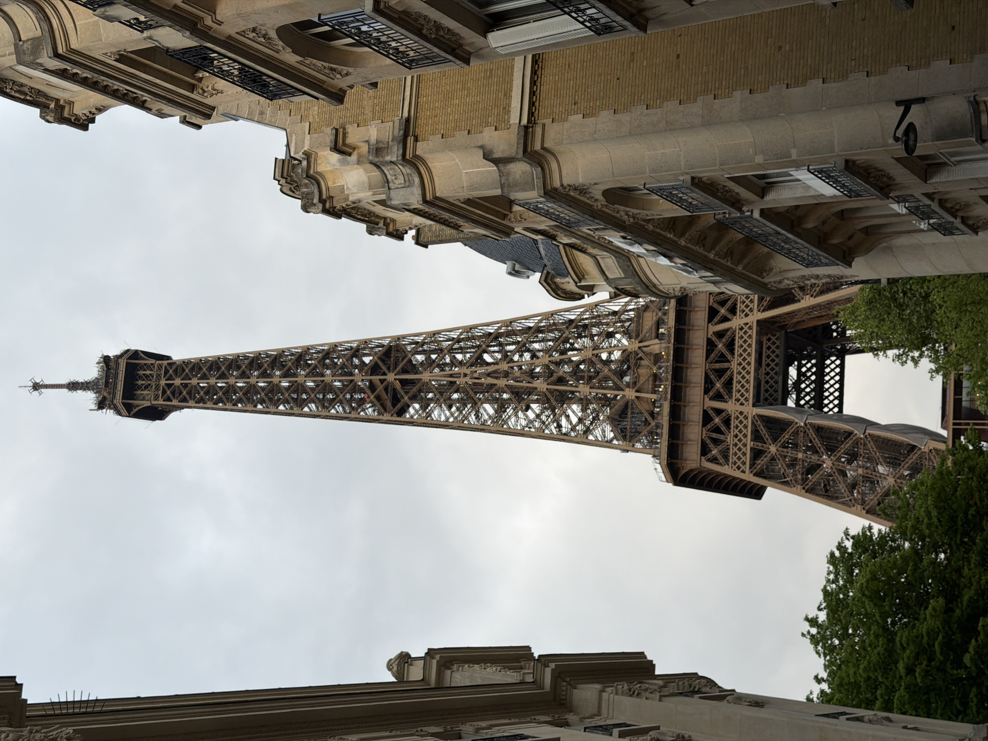Eiffel Tower photographed from street level under cloudy Paris sky